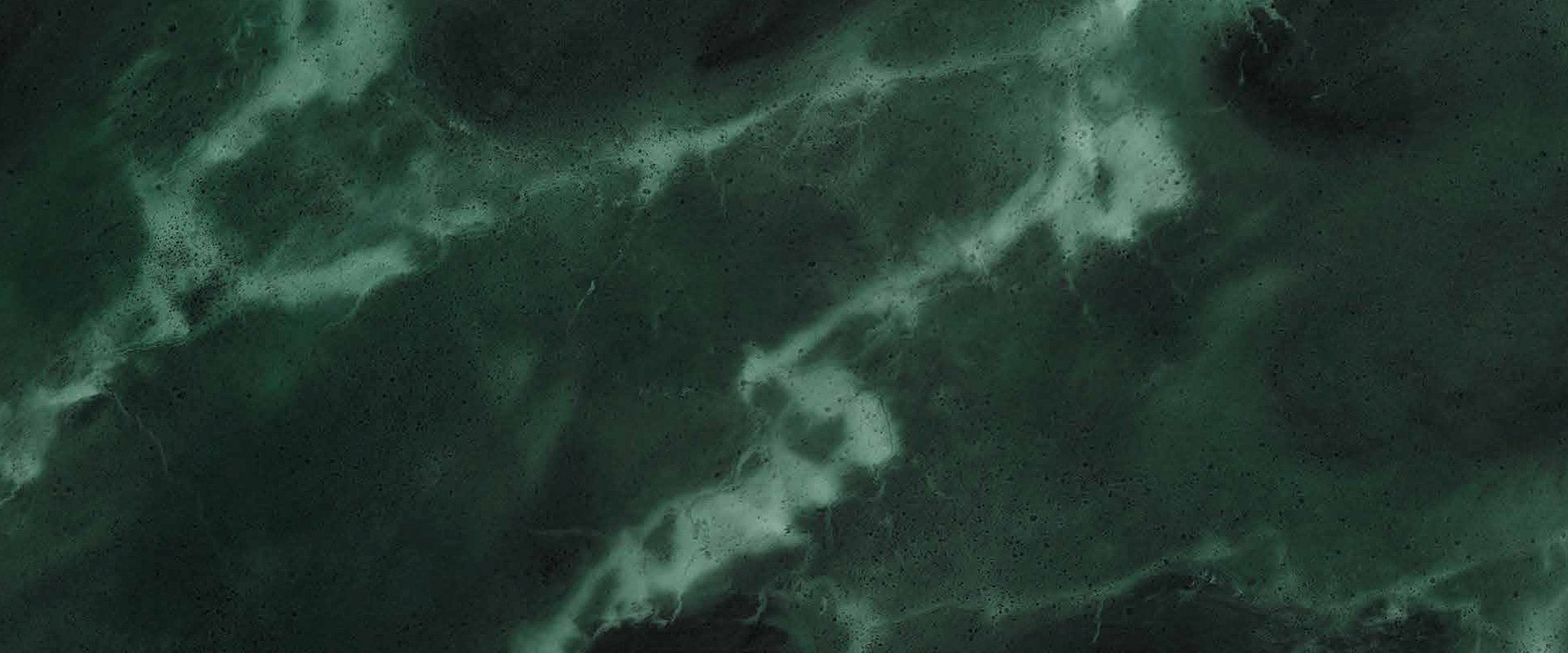 Dark green marble texture with swirling white veins and cloudy patterns, resembling natural stone used in countertops or tiles. The surface appears smooth and polished, with a mix of light and dark green shades.