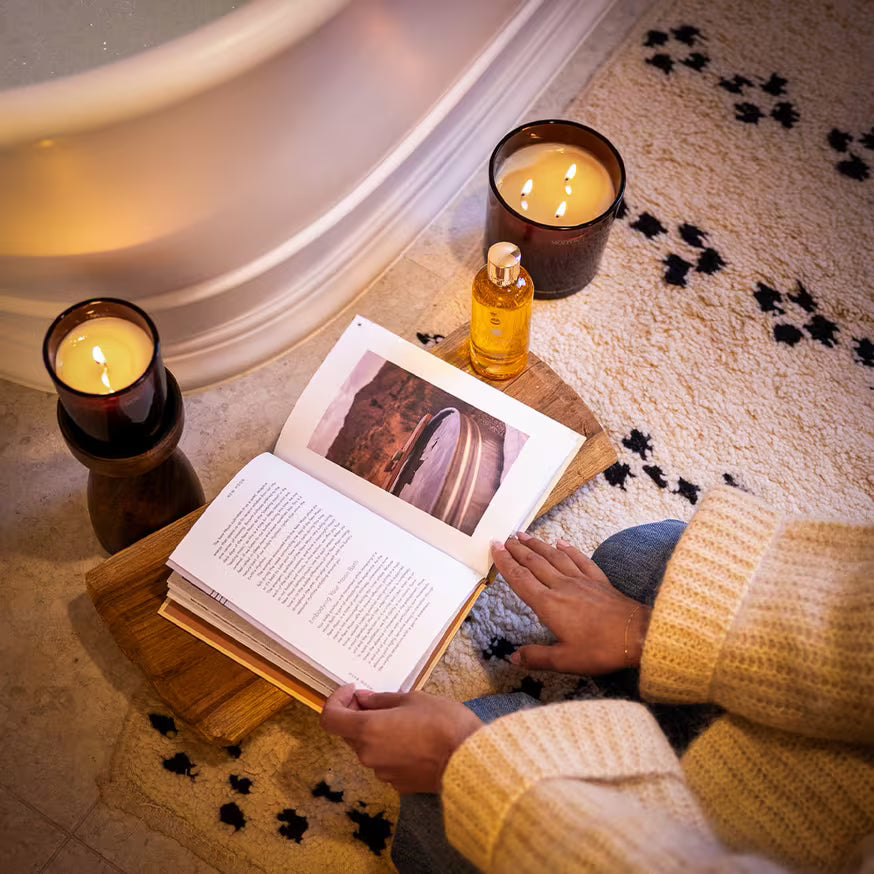 A person reading a book next to candles.