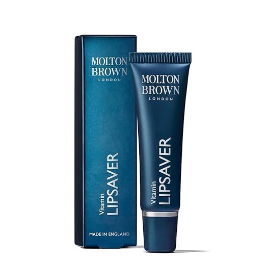 A dark blue tube of MoltonBrown Nederlands Vitamin Lipsaver 10ml stands upright next to its matching box, both showing the brand name and product title in white text, highlighting vitamins that help protect your lips.