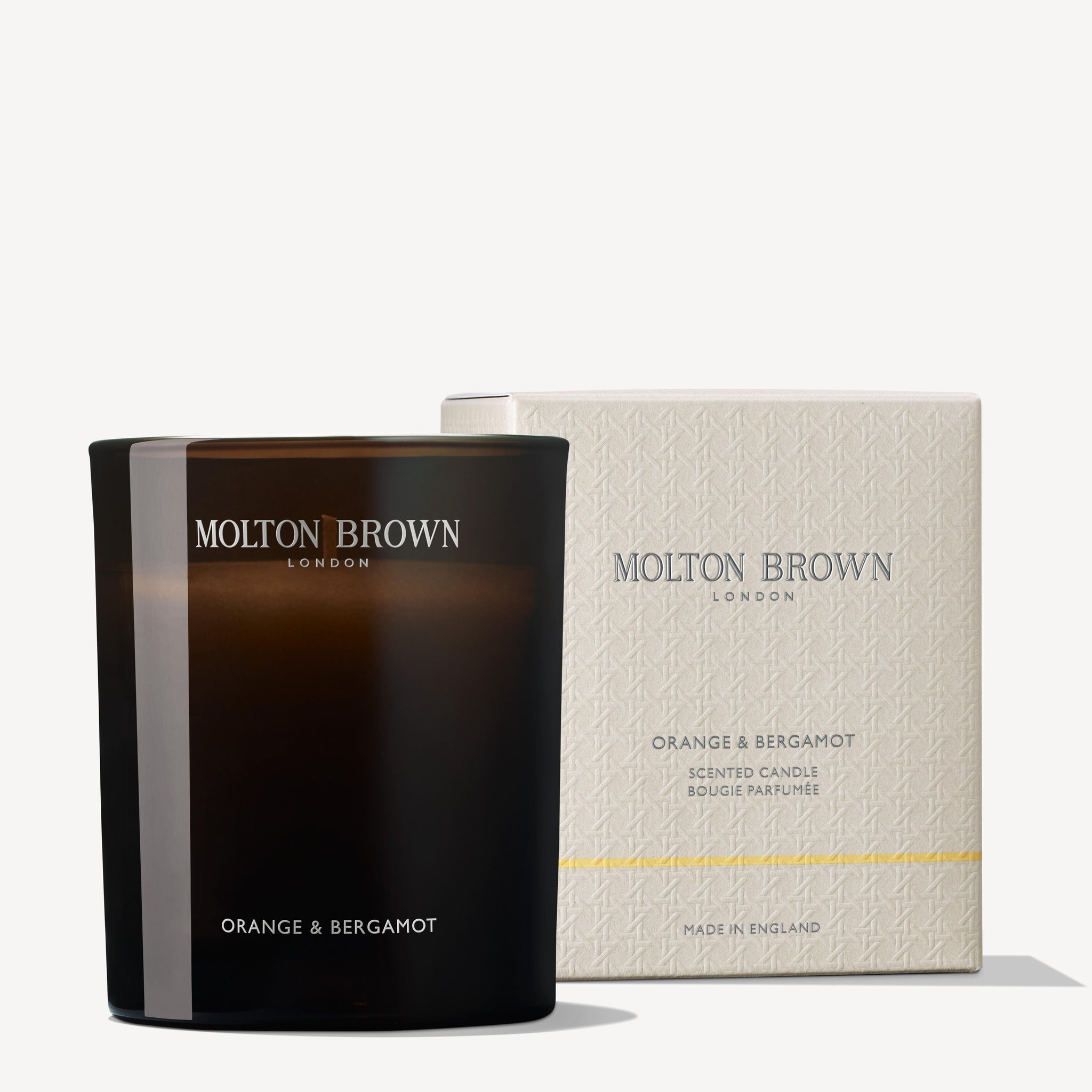 A black MoltonBrown Nederlands Orange & Bergamot Signature Kaars 190g is placed before its textured white and gold box, featuring the brand’s logo and the Orange & Bergamot geurkaars scent name.