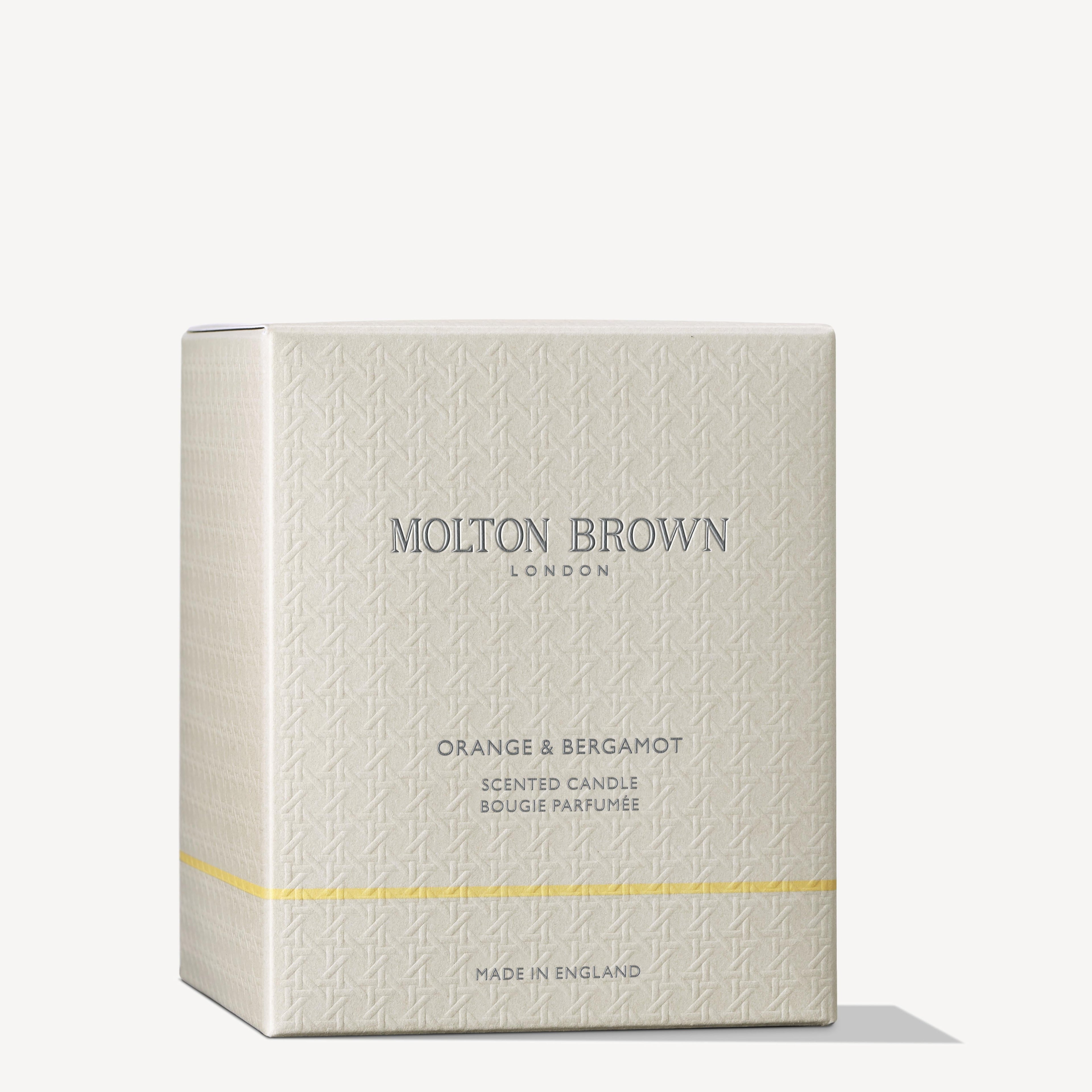 A cream-colored box with subtle patterns labeled MoltonBrown Nederlands. Below, it reads Orange & Bergamot Signature Kaars 190g: een enkele lont kaars voor een energieke gloed. MADE IN ENGLAND staat ook op de doos.