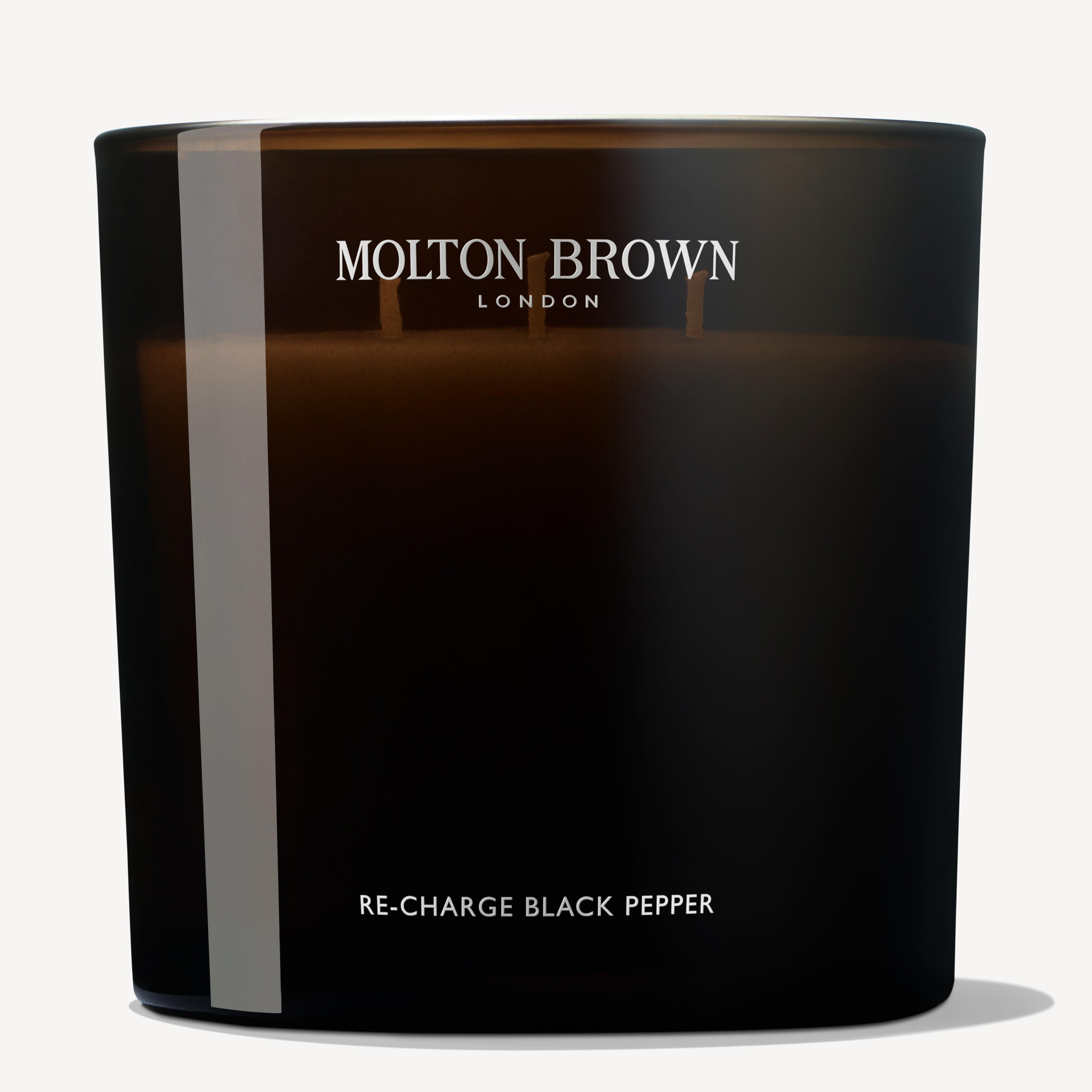 The Re-charge Black Pepper Luxury Kaars 600g by MoltonBrown Nederlands comes in a sleek black glass holder with white text, featuring two wicks for an elegant glow—perfect for adding style to any woonkamer.