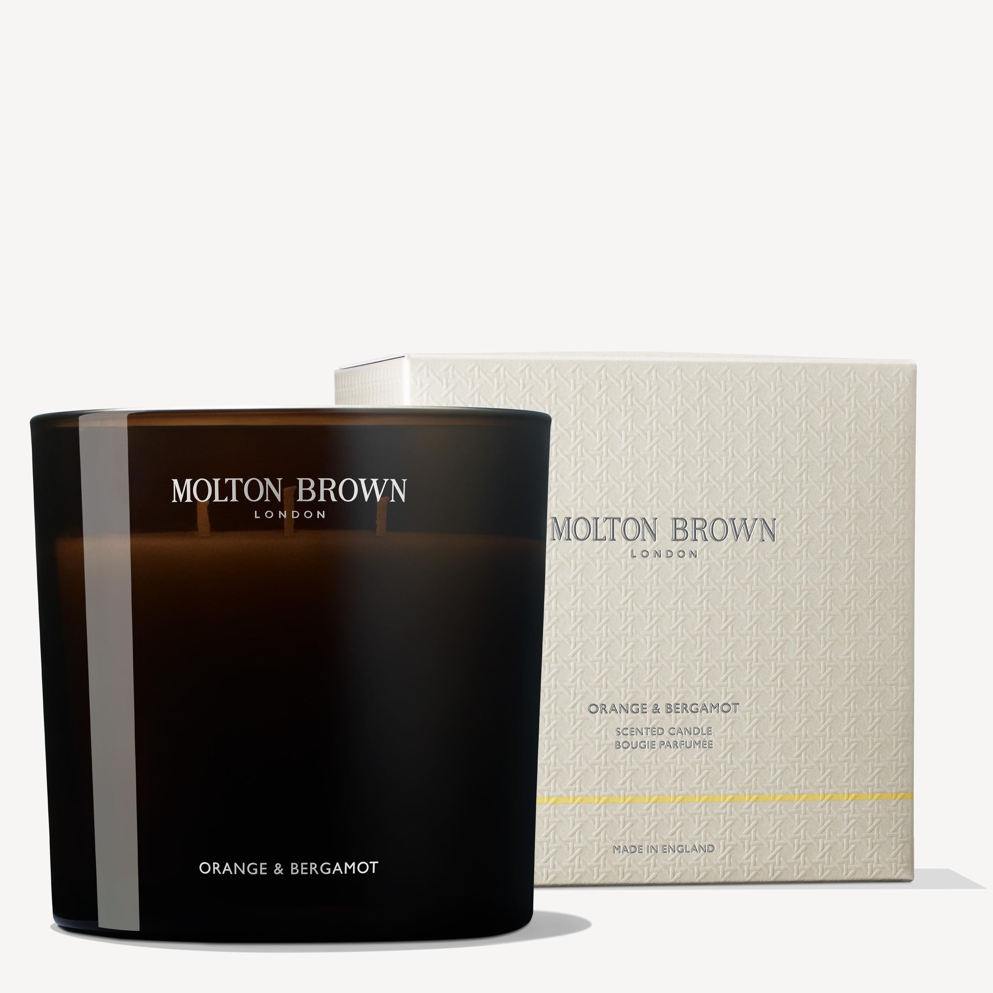 A dark glass MoltonBrown Nederlands Orange & Bergamot Luxury Kaars 600g is placed before its textured cream box, both showing the brand logo and product details.