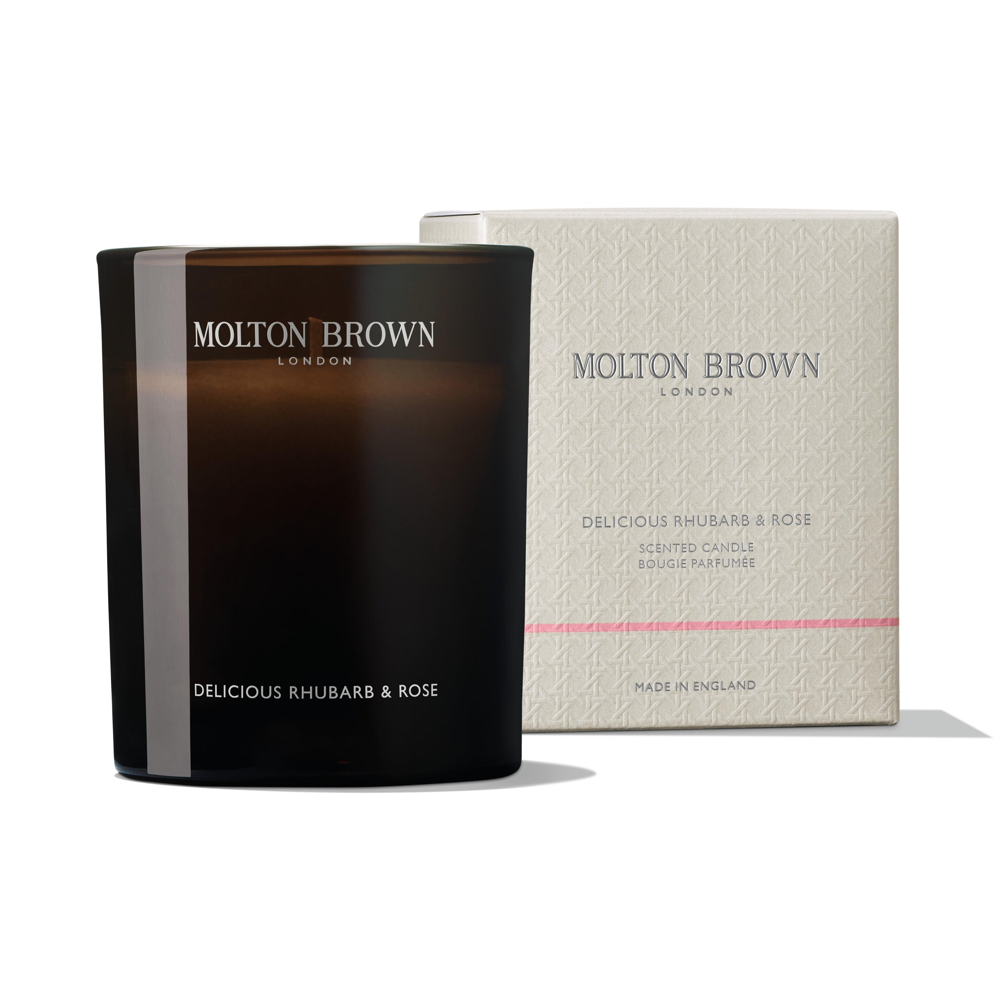 The MoltonBrown Nederlands Delicious Rhubarb & Rose Signature Kaars 190g comes in a dark glass holder with elegant branding, placed next to its beige textured box featuring scent and product details.