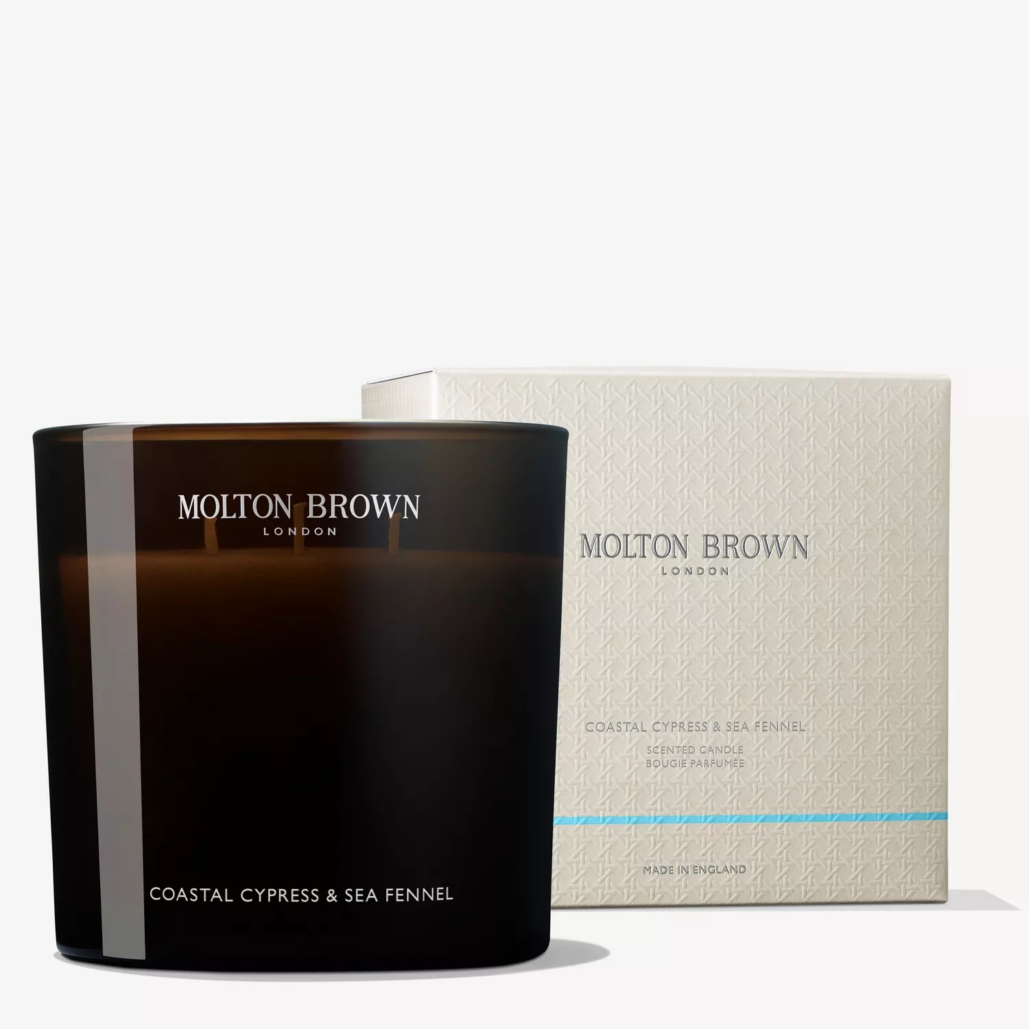 The MoltonBrown Nederlands Coastal Cypress & Sea Fennel Luxury kaars 600g sits in front of its light-patterned box, both showing the MoltonBrown logo and scent name.