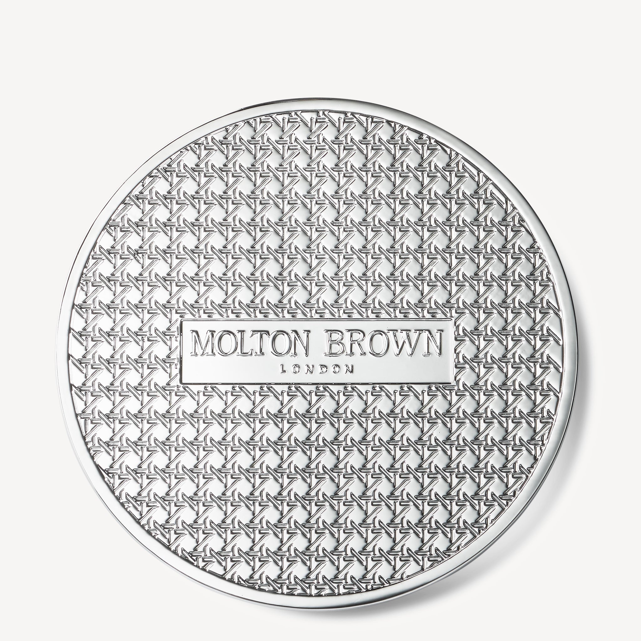 A round, silver-toned Luxury Kaars Lid 154g by MoltonBrown Nederlands features a geometric star pattern and a raised rectangular label in the center that reads Molton Brown London.