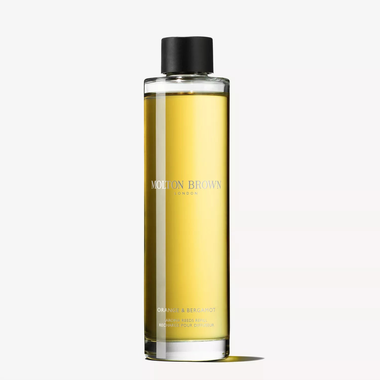 A clear bottle with golden liquid, labeled MoltonBrown Nederlands. It has a black cap and minimalistic design. Text reads Fiery Pink Pepper Perfumed Soap 150g, echoing their iconic collections. Background is plain white.