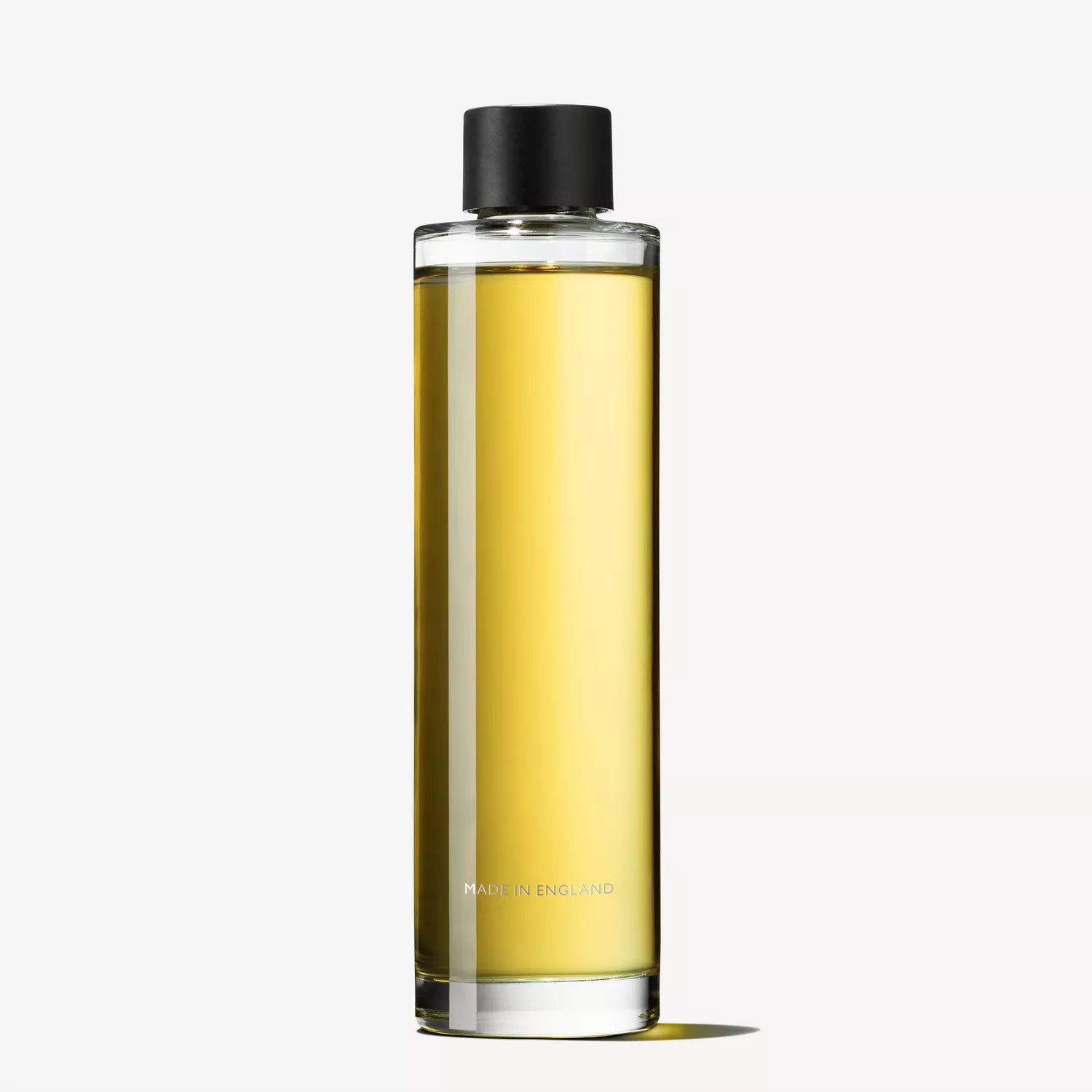 A clear, cylindrical glass bottle containing yellow Fiery Pink Pepper Perfumed Soap (150g) by MoltonBrown Nederlands, with a black cap and "Made in England" near the base, set against a plain white background.