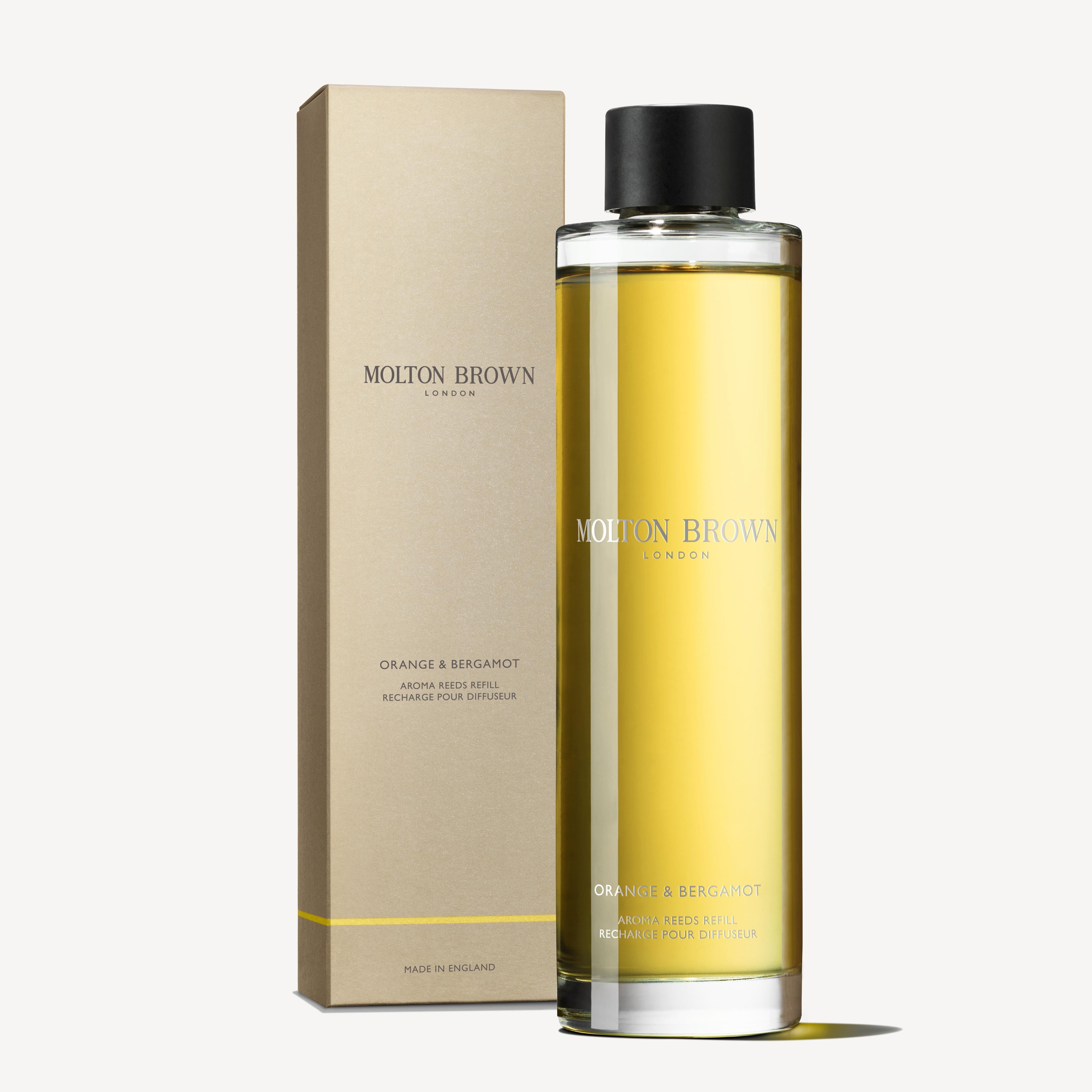 De Orange & Bergamot Geurstokjes Navulling 150ml van MoltonBrown Nederlands, met een frisse citrusgeur, staat naast de doos—een duurzame keuze voor je interieur.