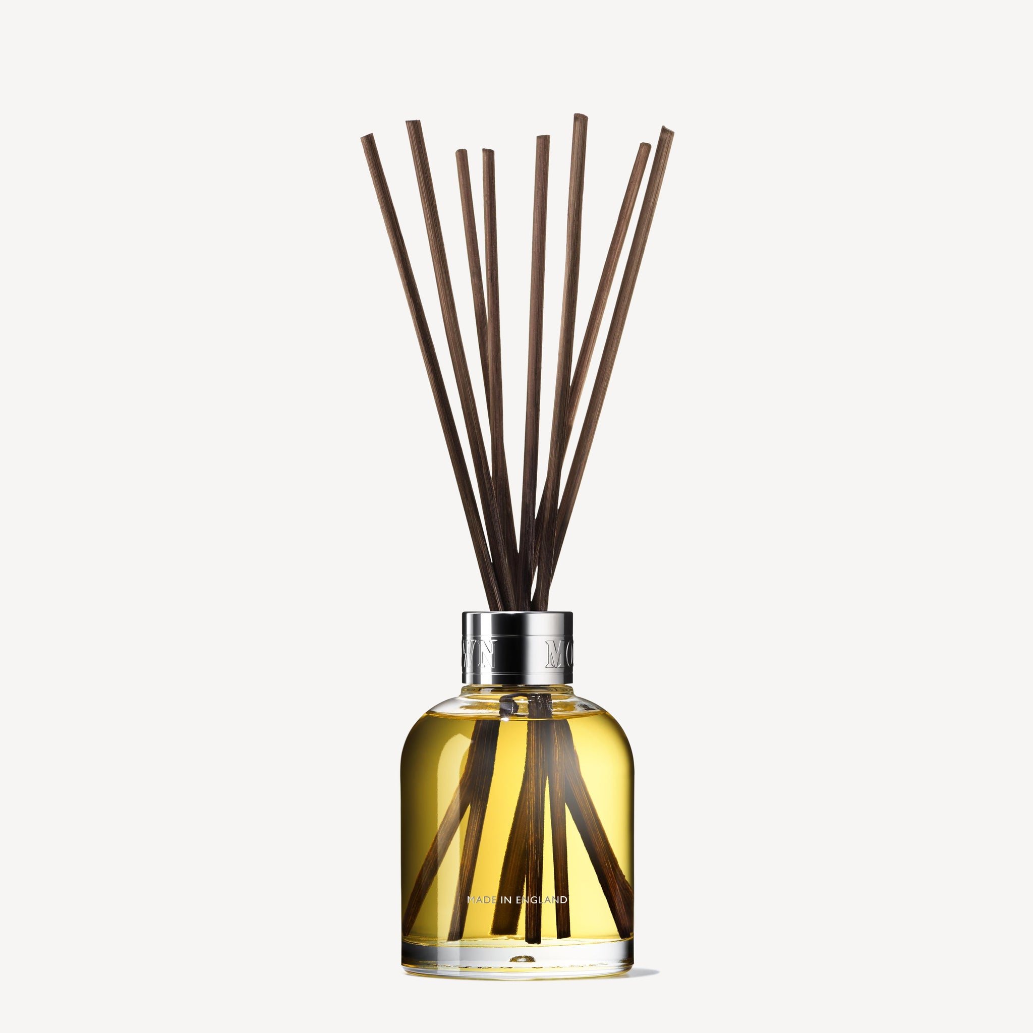 MoltonBrown Nederlands test 2 Orange & Bergamot Geurstokjes 150ml (Copy) features a clear glass bottle with yellow liquid, silver cap, and long dark sticks that diffuse a refreshing citrus scent throughout your room.