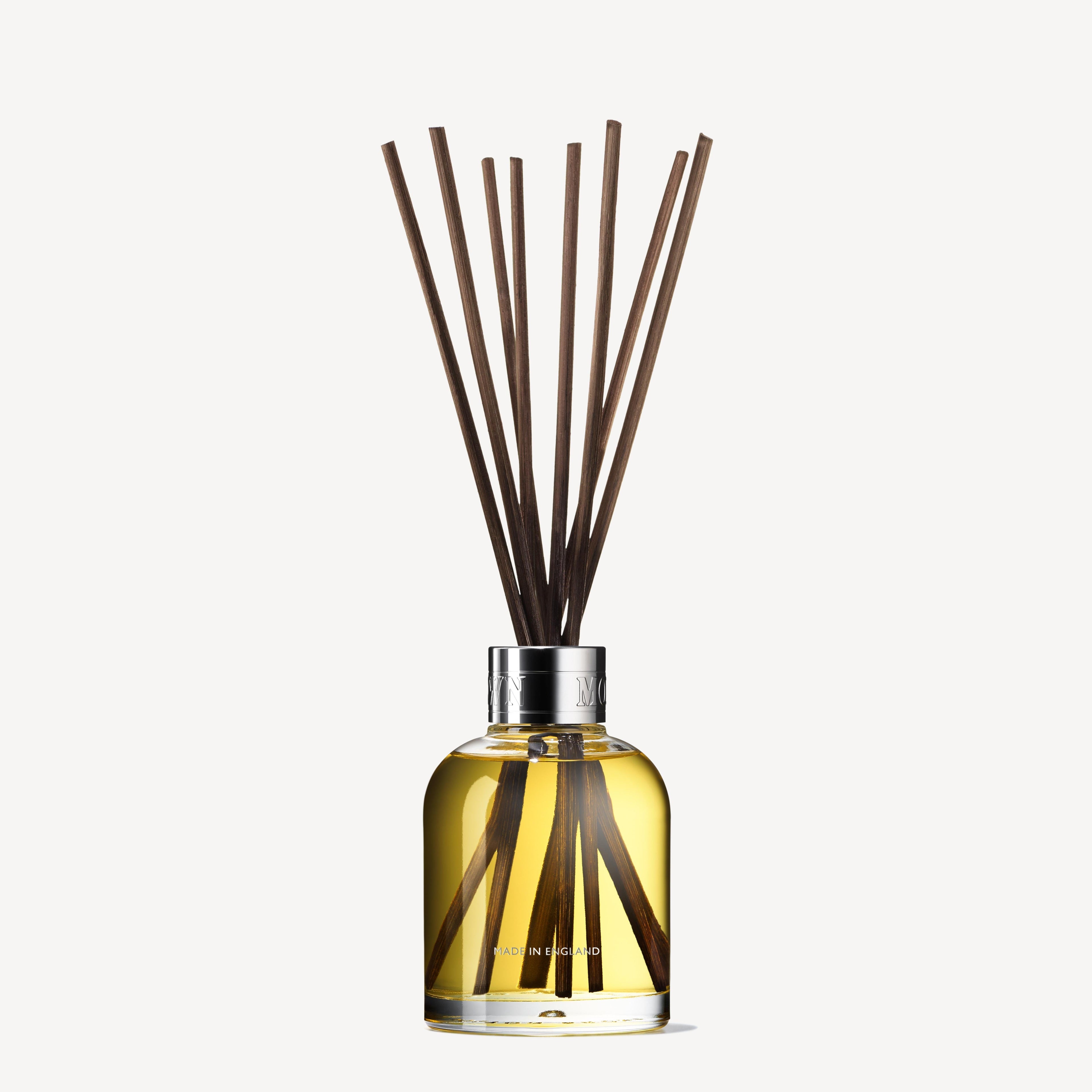 MoltonBrown Nederlands test 2 Orange & Bergamot Geurstokjes 150ml (Copy) features a clear glass bottle with yellow liquid, silver cap, and long dark sticks that diffuse a refreshing citrus scent throughout your room.