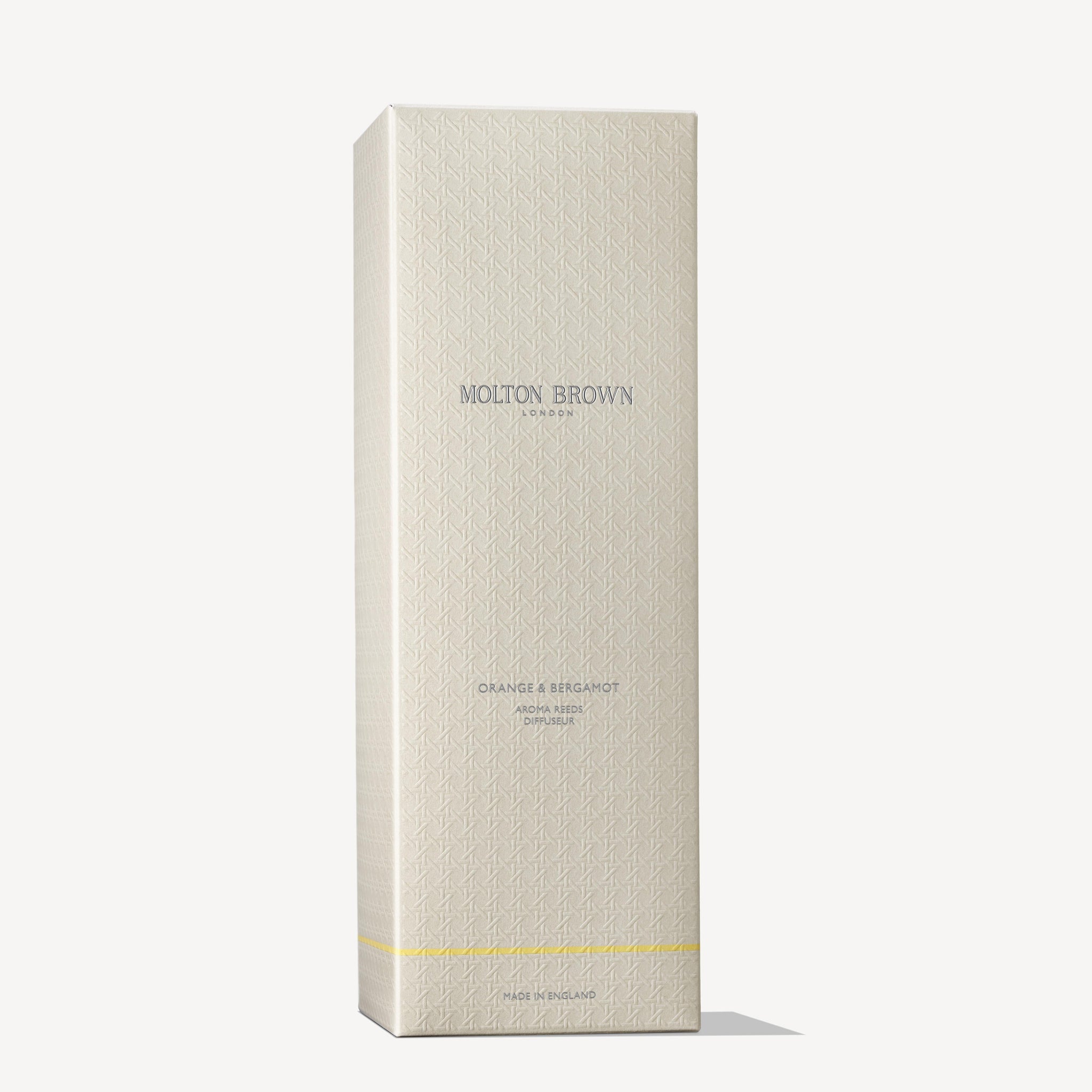 A tall, textured cream box features MoltonBrown Nederlands and test 2 Orange & Bergamot Geurstokjes 150ml (Copy) in silver and gold text, a subtle geometric pattern, gold stripe near the base, and elegant geurstokjes for a citrus scent.