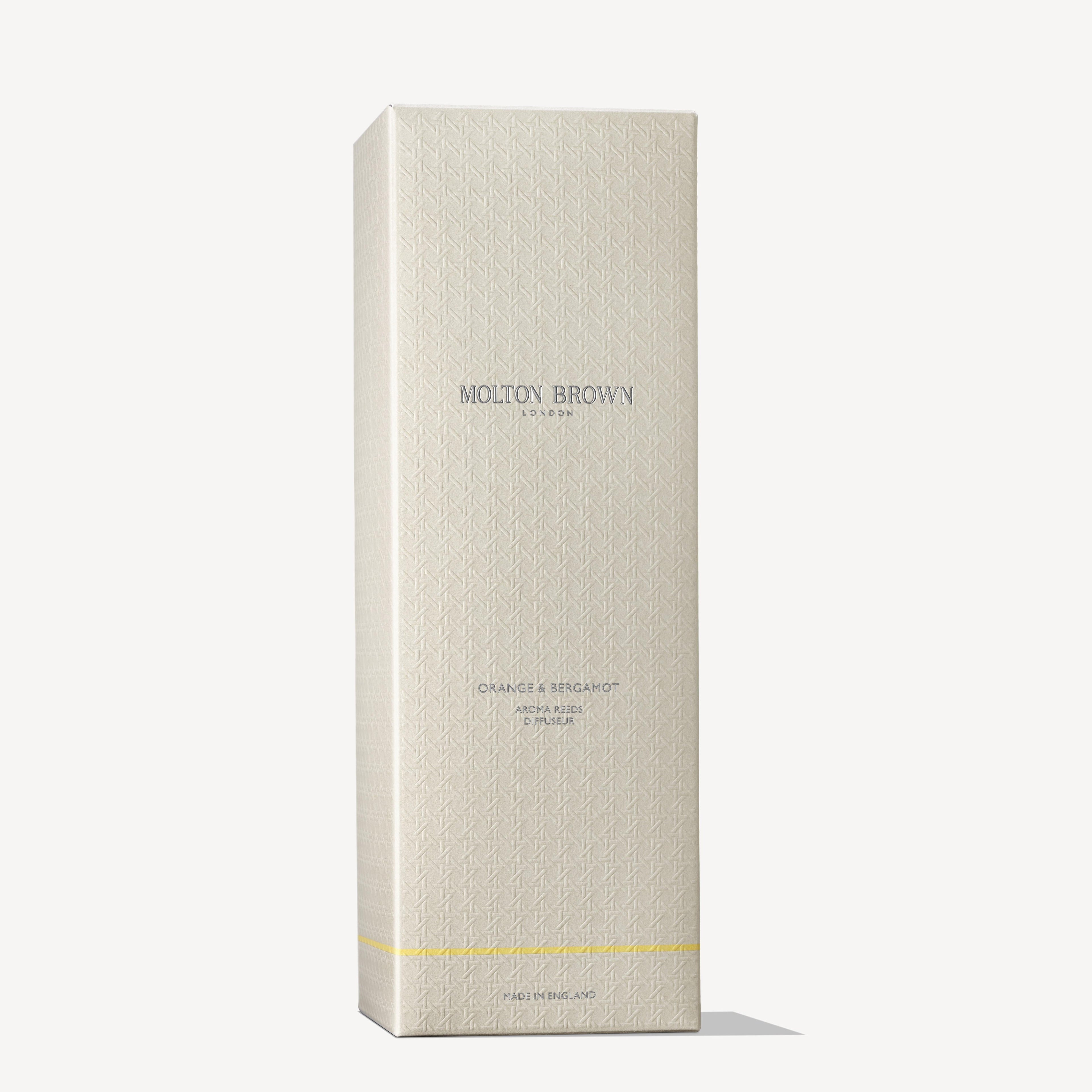 A tall, textured cream box features MoltonBrown Nederlands and test 2 Orange & Bergamot Geurstokjes 150ml (Copy) in silver and gold text, a subtle geometric pattern, gold stripe near the base, and elegant geurstokjes for a citrus scent.