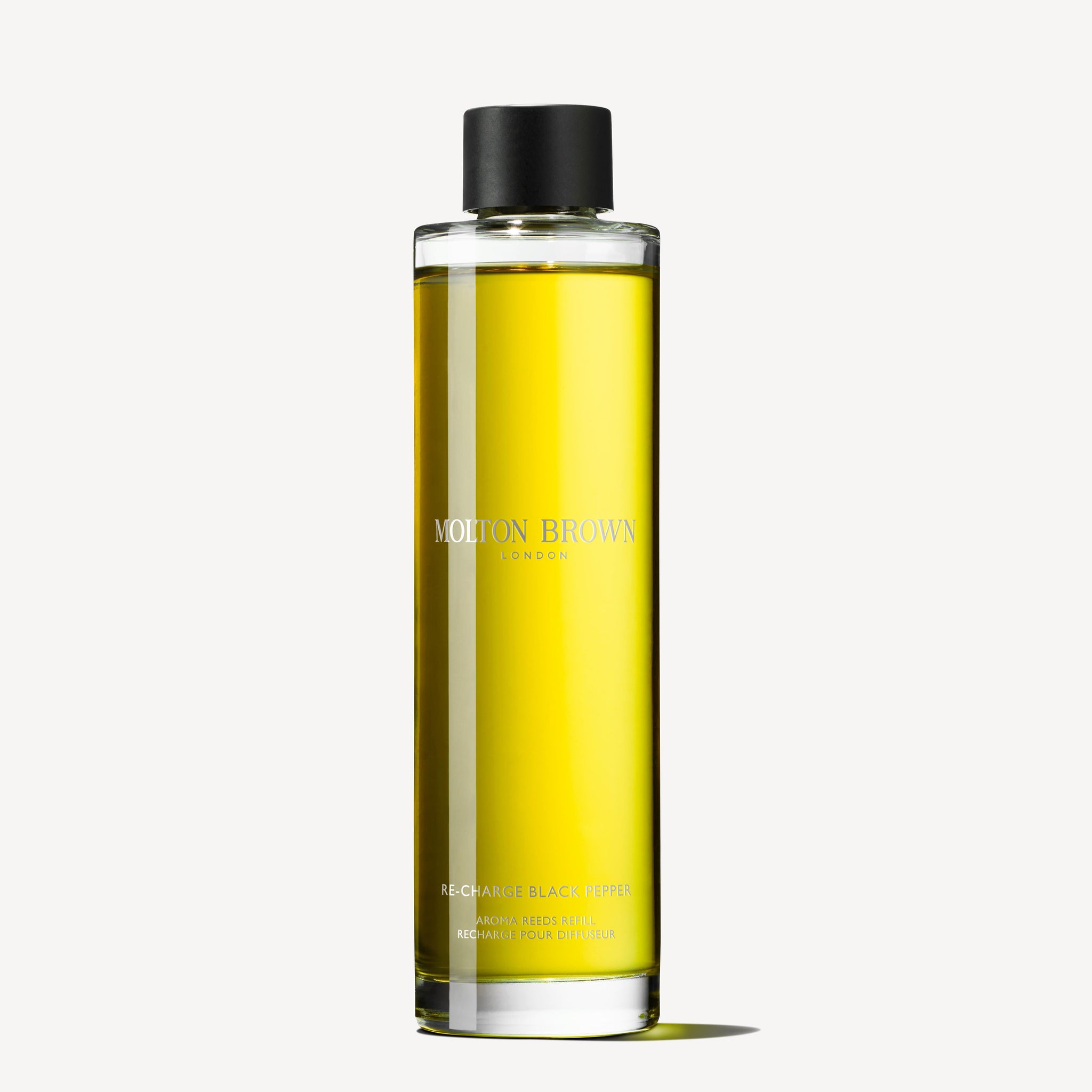 A clear, cylindrical bottle with a black cap labeled MoltonBrown Nederlands Re-charge Black Pepper Geurstokjes Navulling 150ml, filled with yellow liquid and highlighting its houtig-citrus geur against a plain white background.