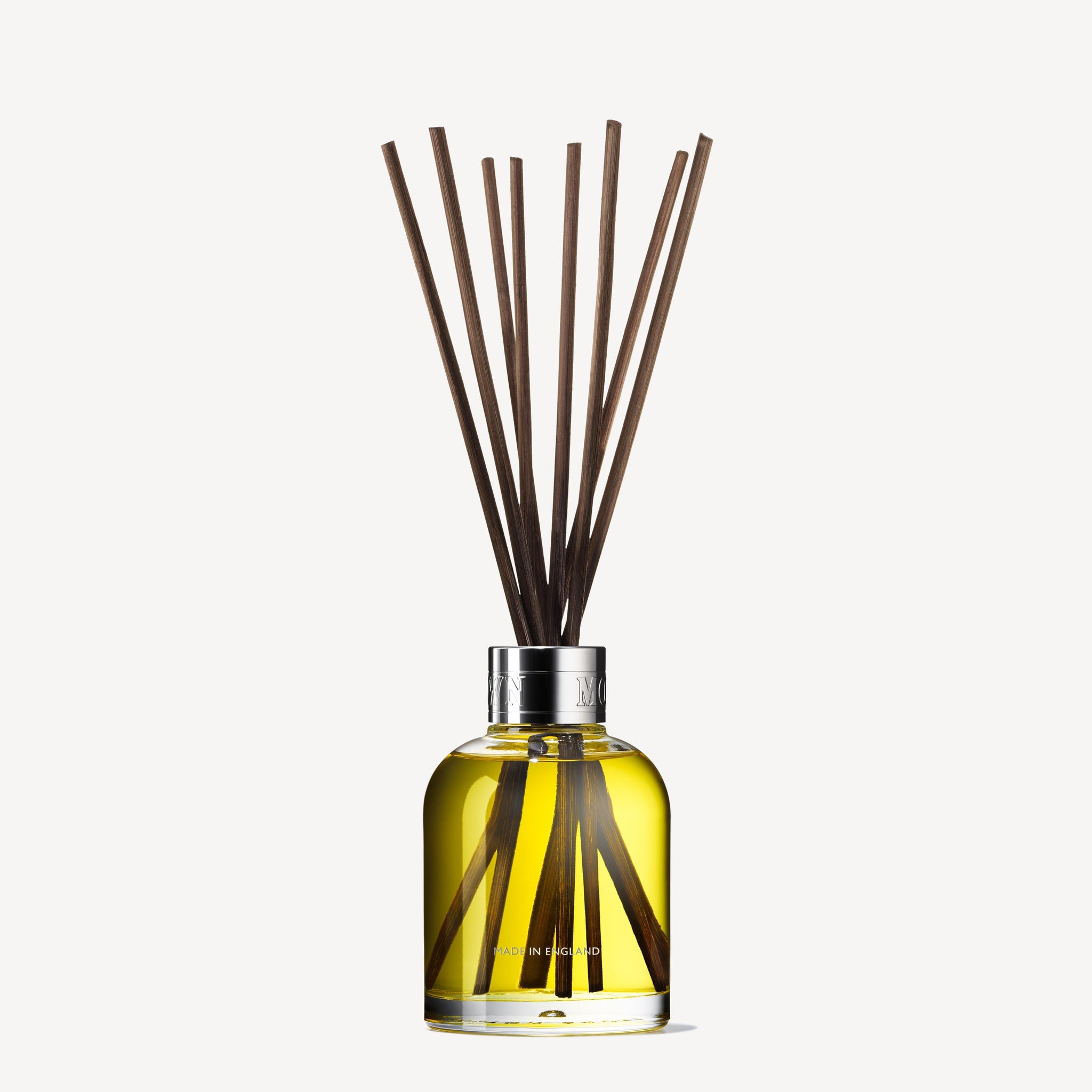 MoltonBrown Nederlands Re-charge Black Pepper Geurstokjes 150ml features a clear glass bottle with yellow liquid and long black sticks, diffusing a houtig-citrus geur as a stylish huisparfum.