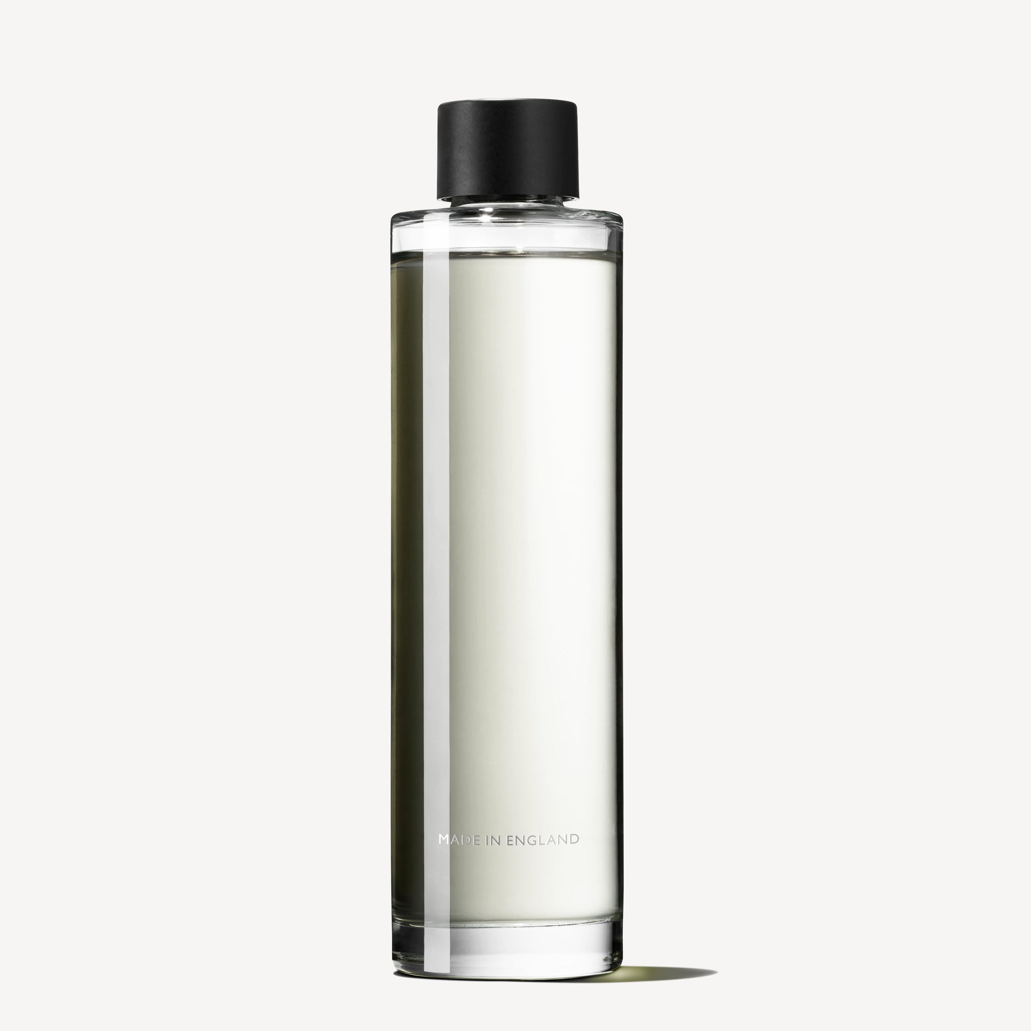 A clear cylindrical glass bottle with a black cap, filled with transparent liquid, labeled "MADE IN ENGLAND," contains MoltonBrown Nederlands Delicious Rhubarb & Rose Geurstokjes Navulling 150ml. Set against a plain white background.