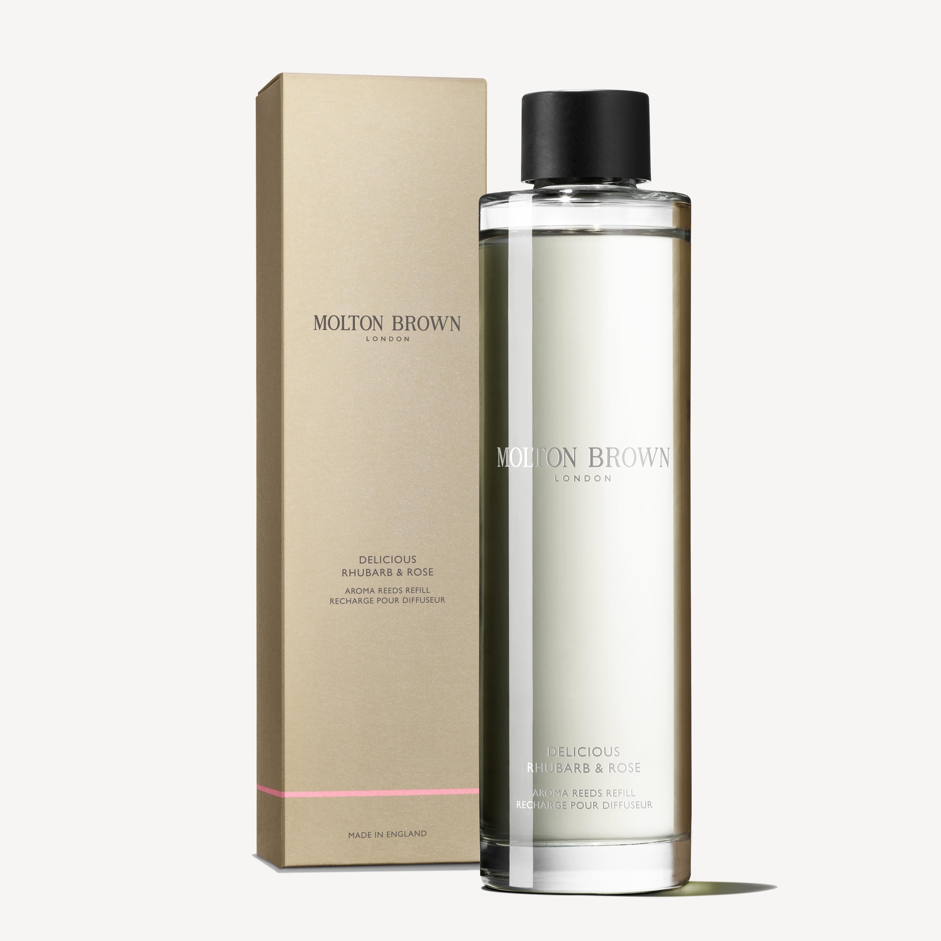A clear bottle labeled MoltonBrown Nederlands Delicious Rhubarb & Rose Geurstokjes Navulling 150ml stands before a matching beige and pink box on a white background.