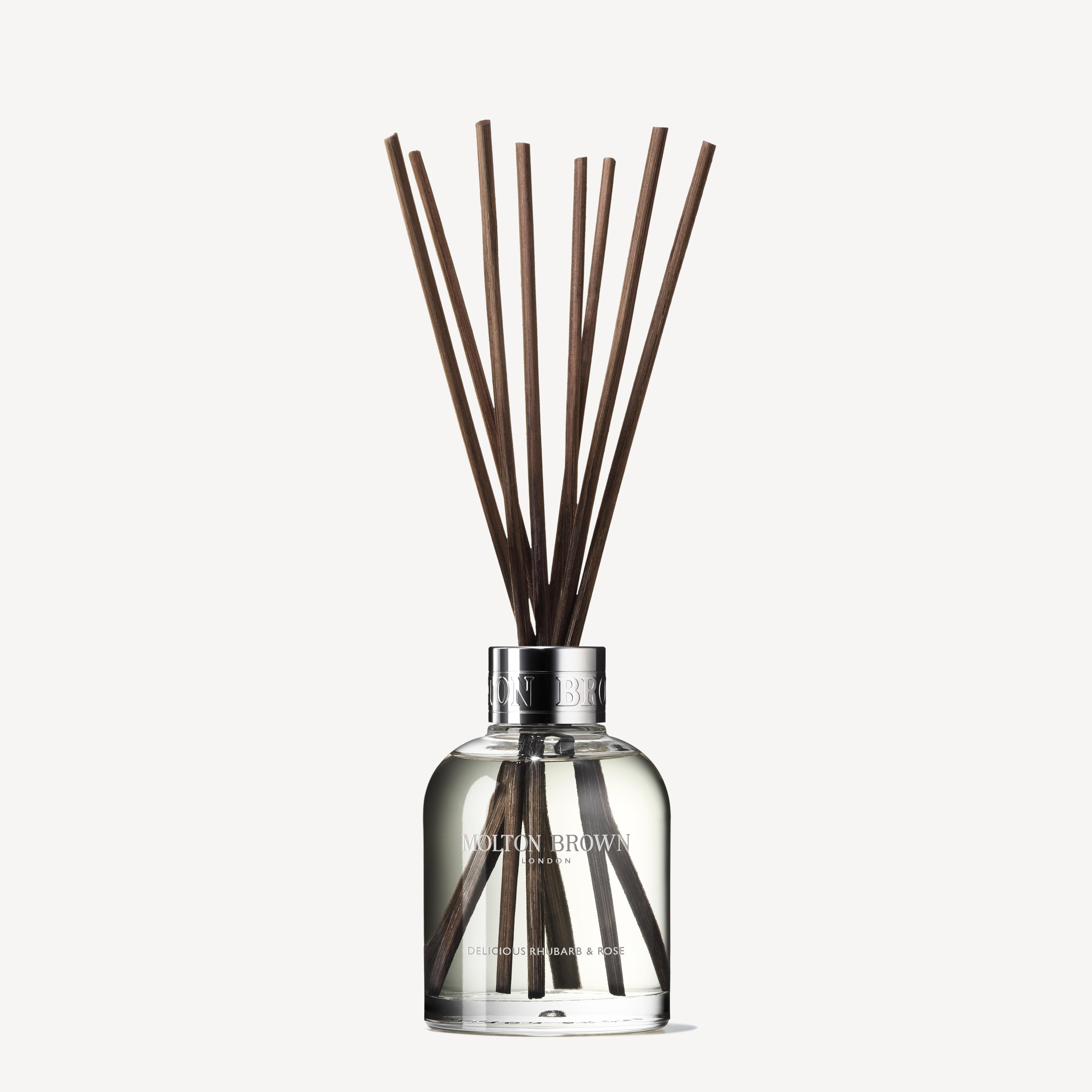 The MoltonBrown Nederlands test 3 Delicious Rhubarb & Rose Geurstokjes 150ml (Copy) diffuser features a clear bottle and brown sticks, adding a bloemig-fruitige geur to your interieur. Displayed against a white background.