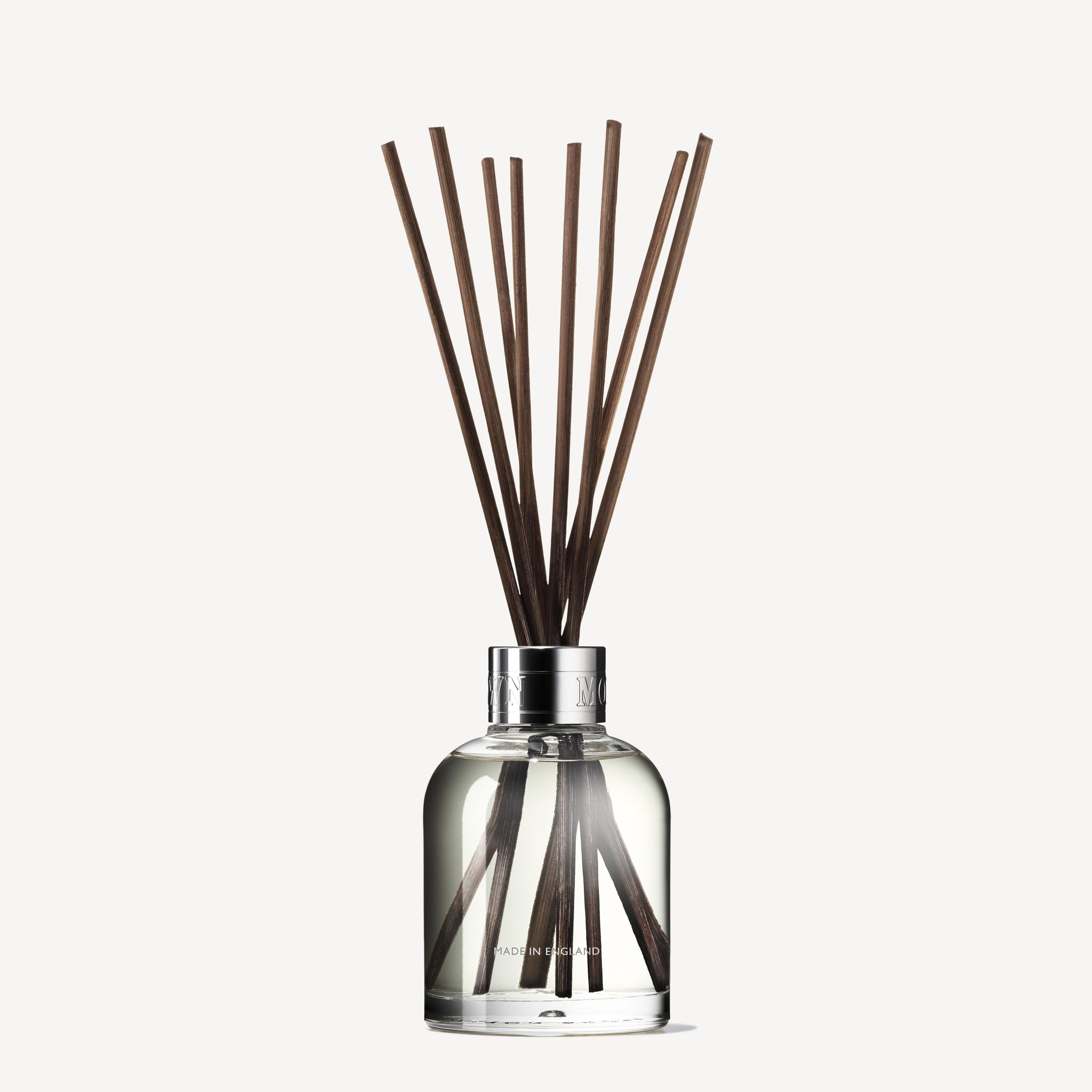 A clear glass diffuser from MoltonBrown Nederlands, filled with 150ml of test 3 Delicious Rhubarb & Rose Geurstokjes, silver-capped and with brown reeds—perfect for adding a floral-fruity aroma to je interieur.