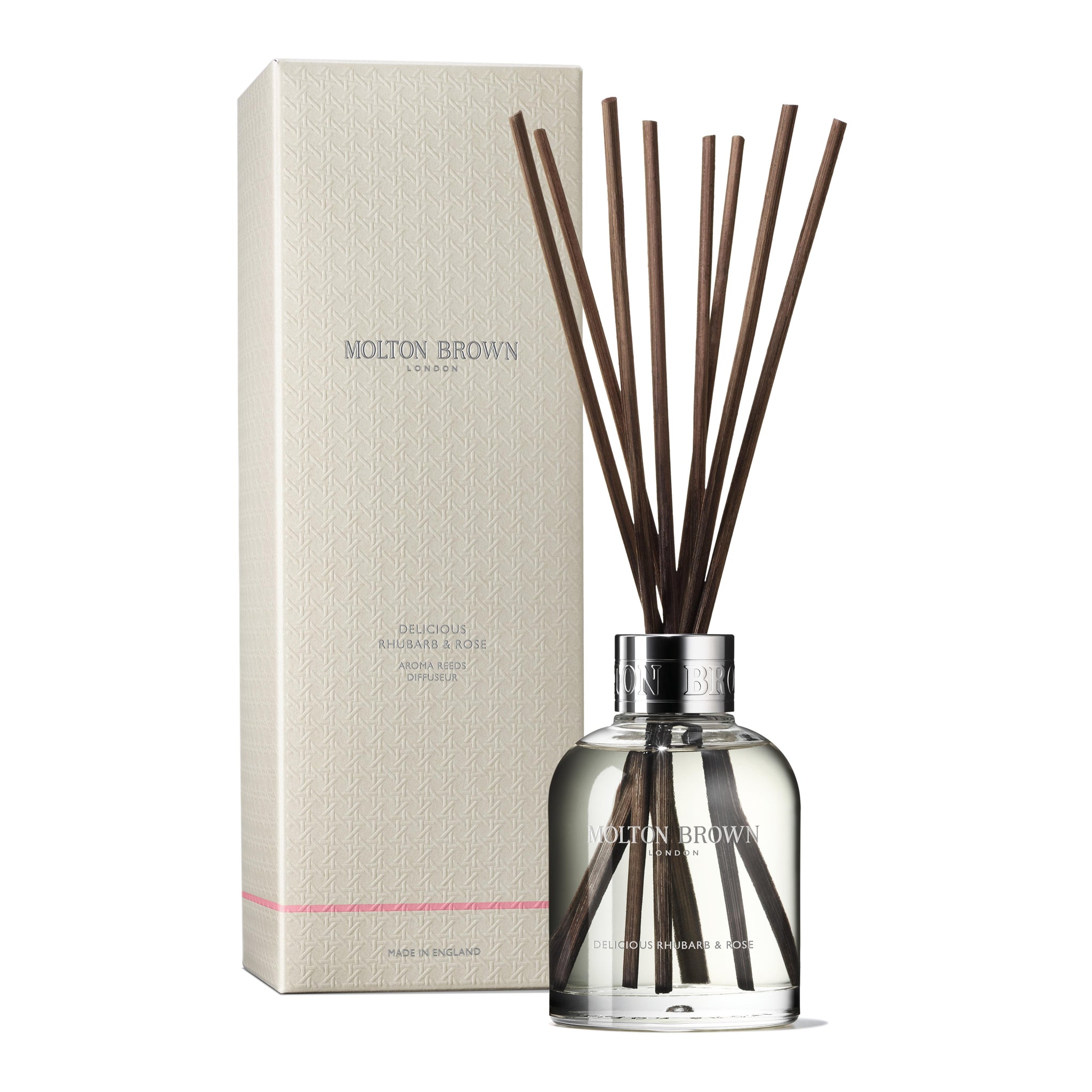 The MoltonBrown Nederlands test 3 Delicious Rhubarb & Rose Geurstokjes 150ml comes in a clear glass bottle with brown reeds beside its cream box, bringing a bloemig-fruitige geur to your interieur. The label shows Delicious Rhubarb & Rose.