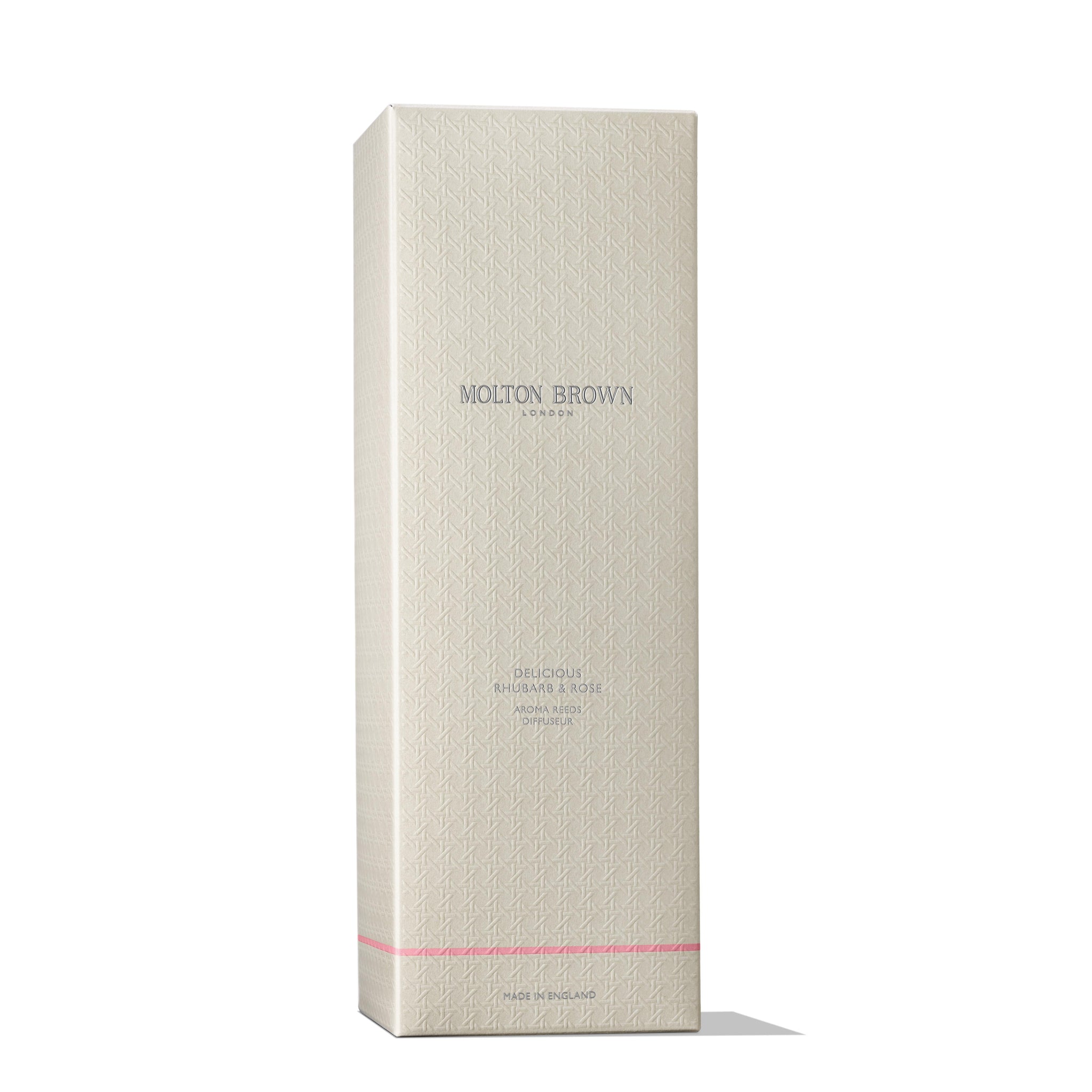 A tall, cream-colored box with geometric patterns and MoltonBrown Nederlands branding in silver and pale purple, plus a thin pink line near the base, houses the test 3 Delicious Rhubarb & Rose Geurstokjes 150ml—perfect for a bloemig-fruitige geur.