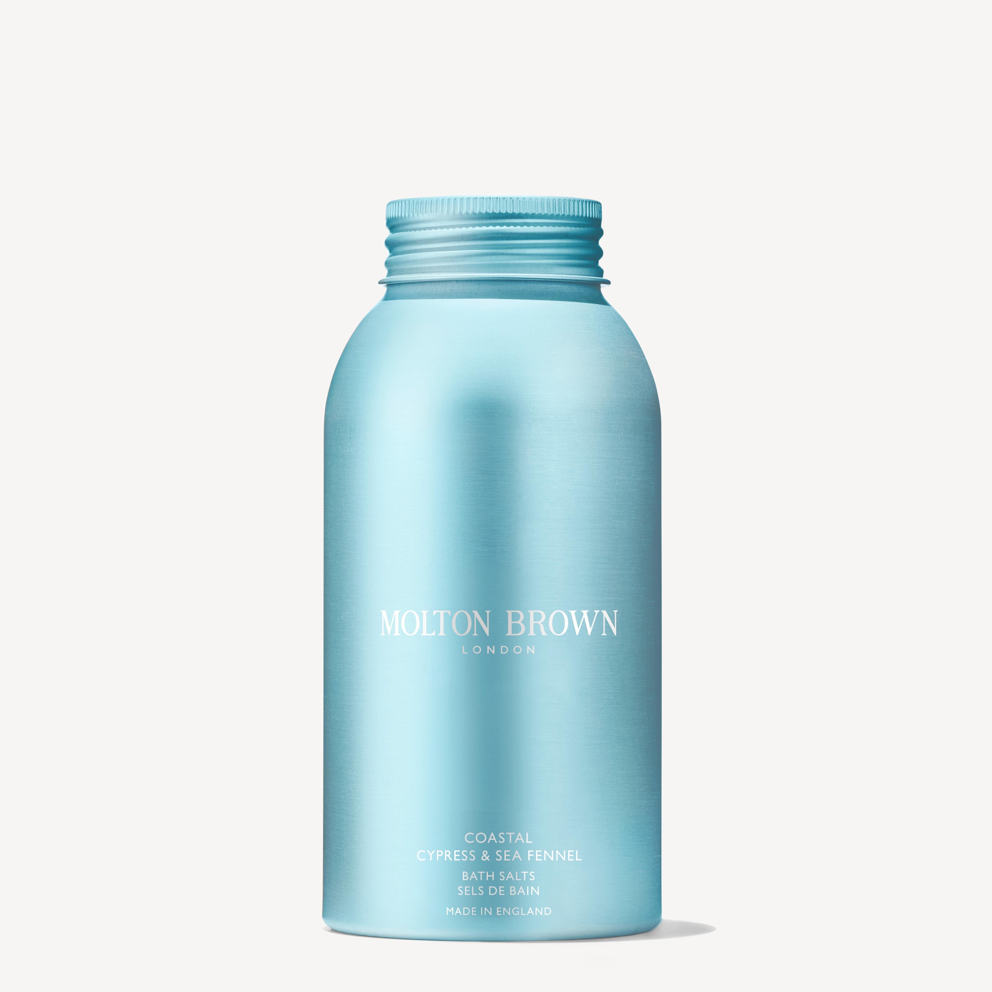 A metallic light blue 300g bottle of MoltonBrown Nederlands Coastal Cypress & Sea Fennel Badzout with a screw cap stands upright against a white background—ideal to pair with your favorite handzeep for a refreshing wash.