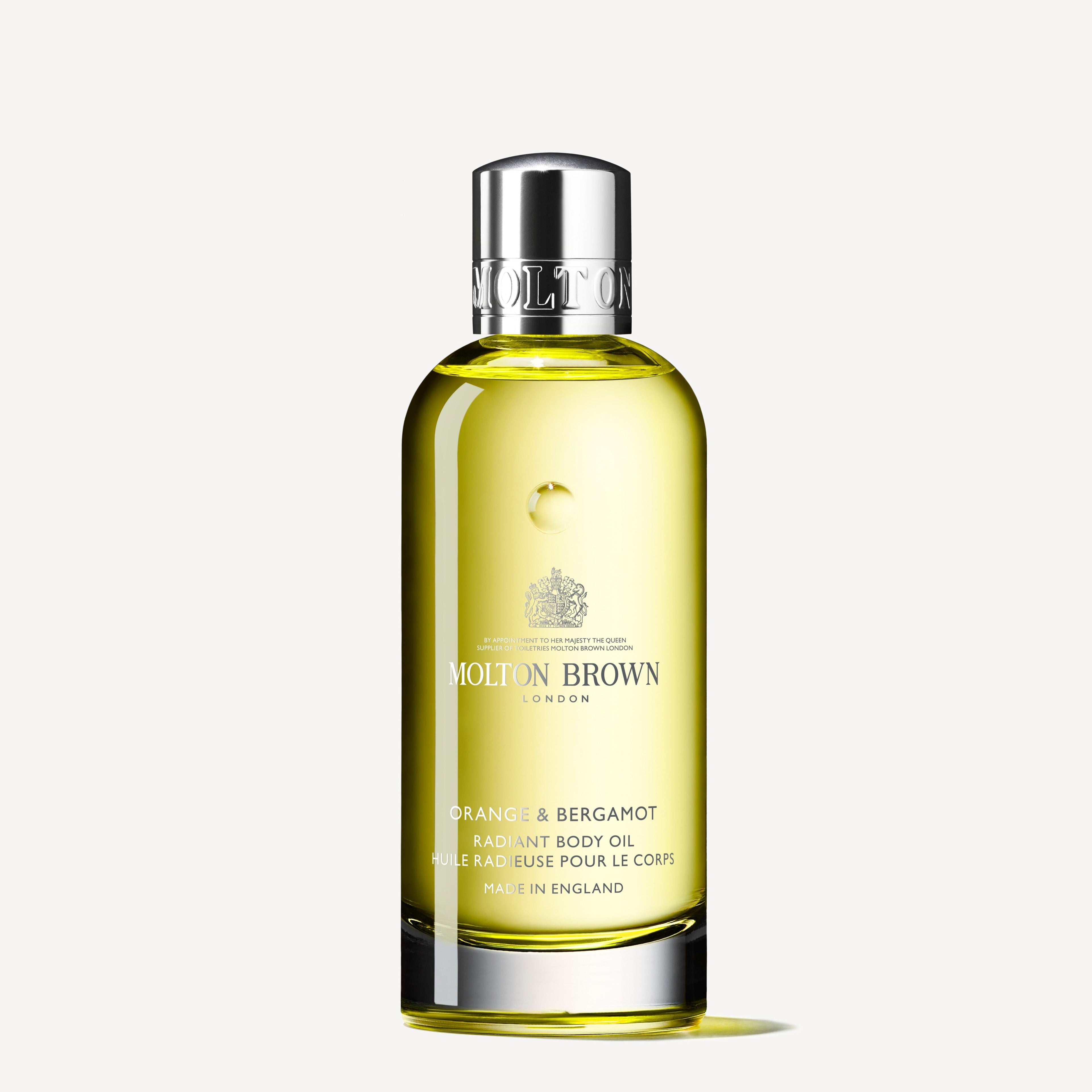 A clear bottle of MoltonBrown Nederlands Orange & Bergamot Radiant Lichaamsolie 100ml with a silver cap, filled with yellow oil, is displayed against a white background.