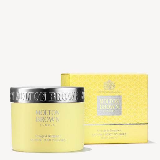 A yellow jar of MoltonBrown Nederlands Orange & Bergamot Radiant Body Polisher 275g with a silver lid stands in front of its matching patterned box, both featuring the MoltonBrown Londen logo and product details.