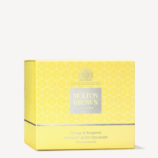 A yellow box of MoltonBrown Nederlands Orange & Bergamot Radiant Body Polisher 275g, with a subtle pattern and silver accents, notes it is made in England.
