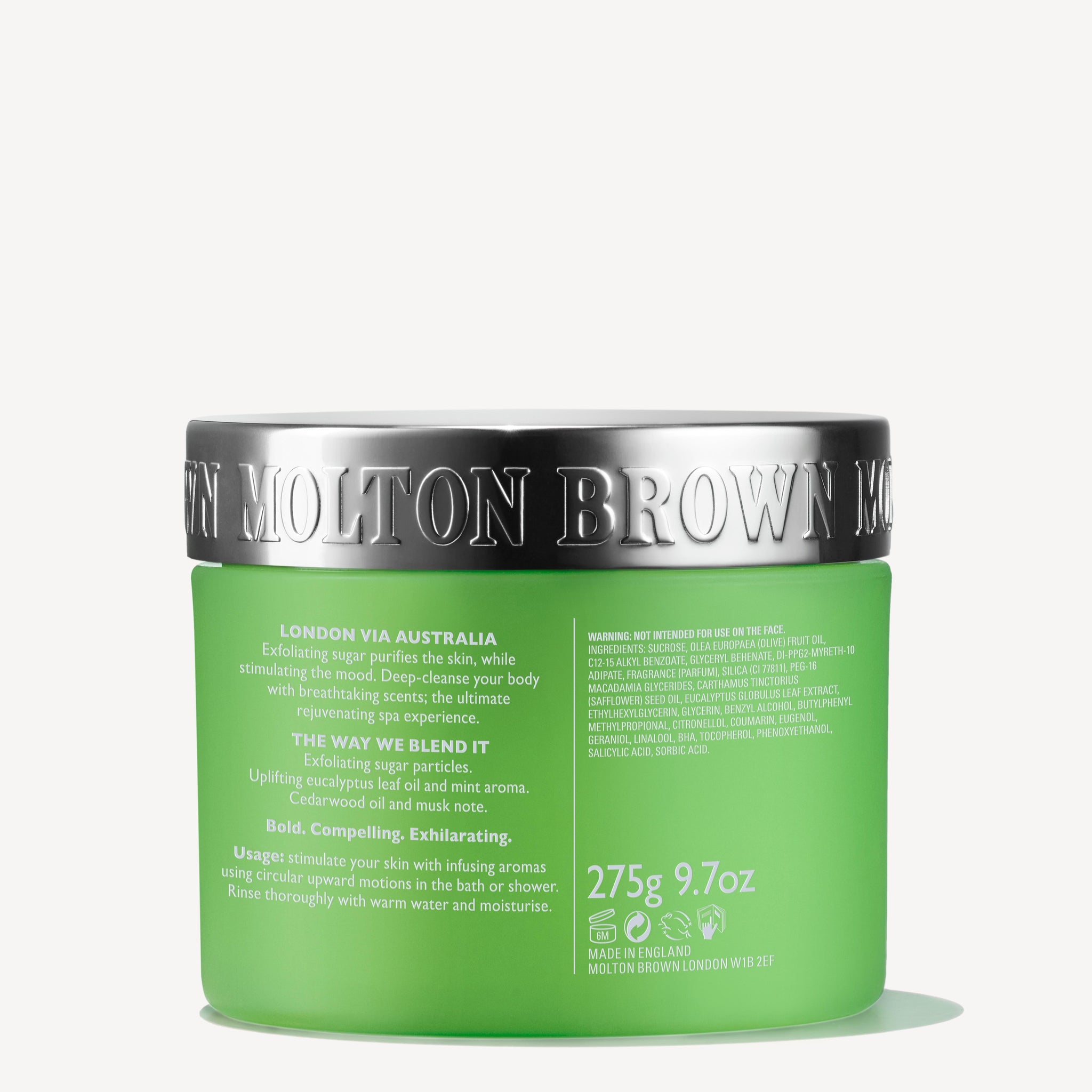 A green 275g tub of MoltonBrown Nederlands Infusing Eucalyptus Stimulating Body Polisher with a metallic silver lid, featuring jojoba korrels and a houtig-citrus geur. The white label displays product and usage details in white text.