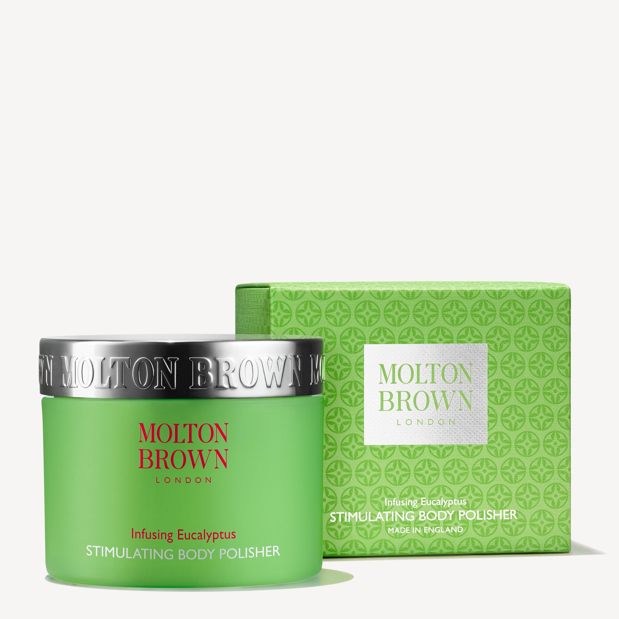 A green jar and box of MoltonBrown Nederlands Infusing Eucalyptus Stimulating Body Polisher 275g, with silver and red accents, geometric patterns, exfoliating jojoba korrels, for a houtig-citrus geur.