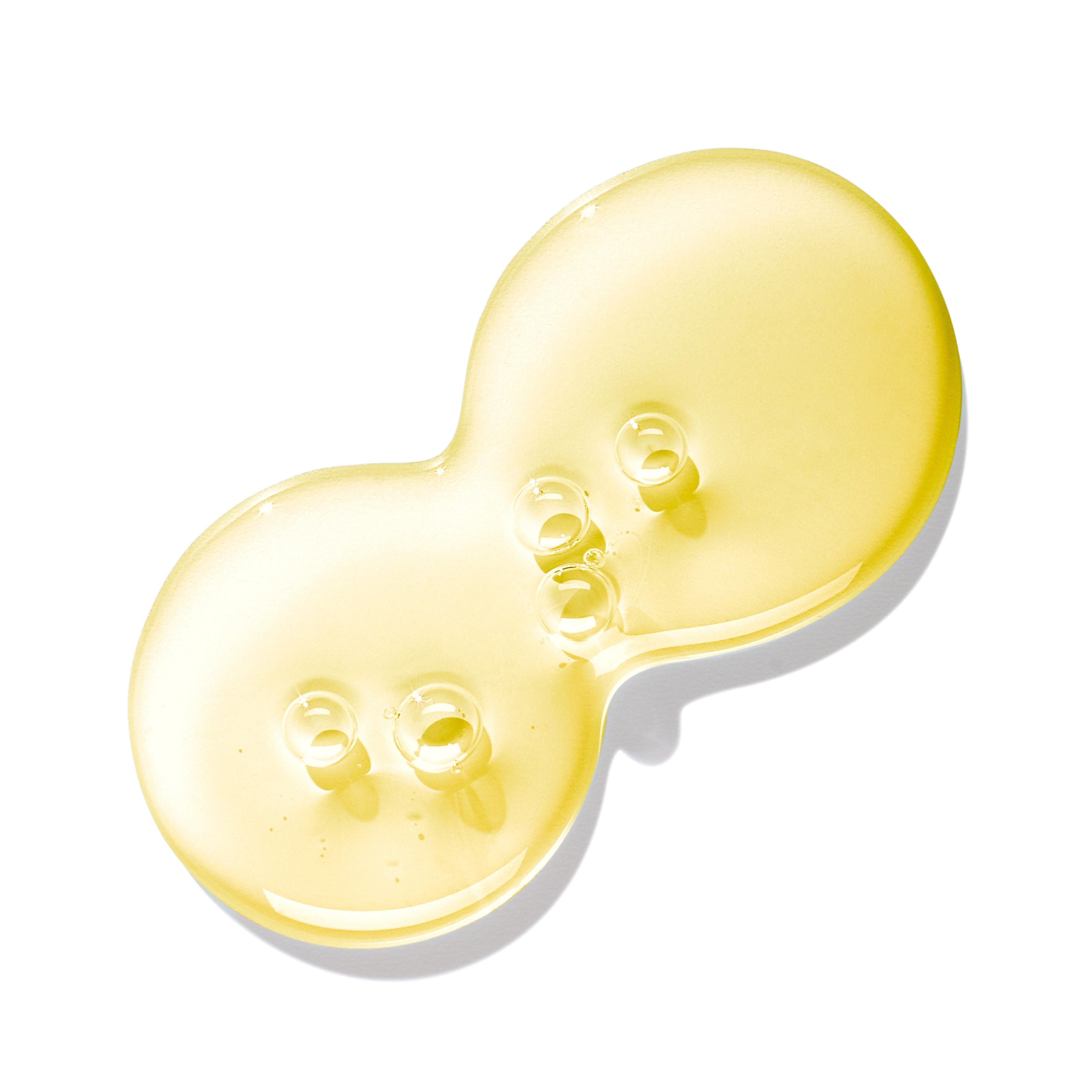 A close-up of a transparent yellow liquid with bubbles, shaped like two overlapping circles—an essence found in MoltonBrown Nederlands Purifying Shampoo With Indian Cress 300ml for shiny hair.