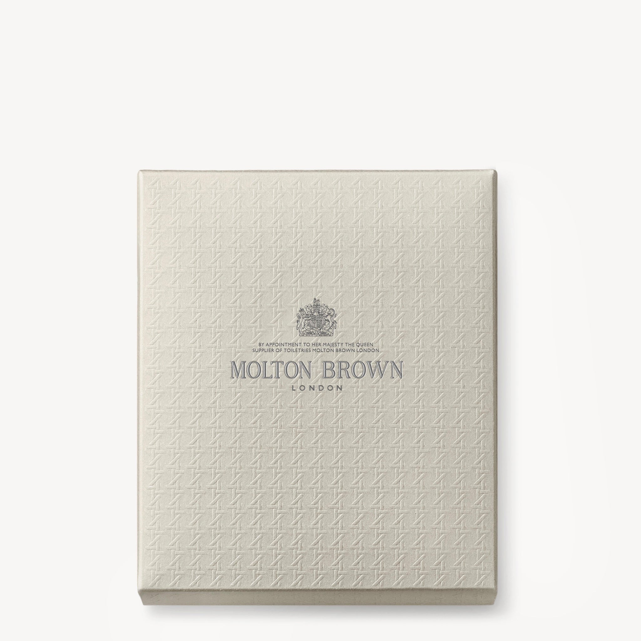 A square, textured, cream-colored Aromatic & Ambery Fragrance Ontdekkingsset gift box from MoltonBrown Nederlands features a subtle pattern and elegant silver lettering centered on the lid.