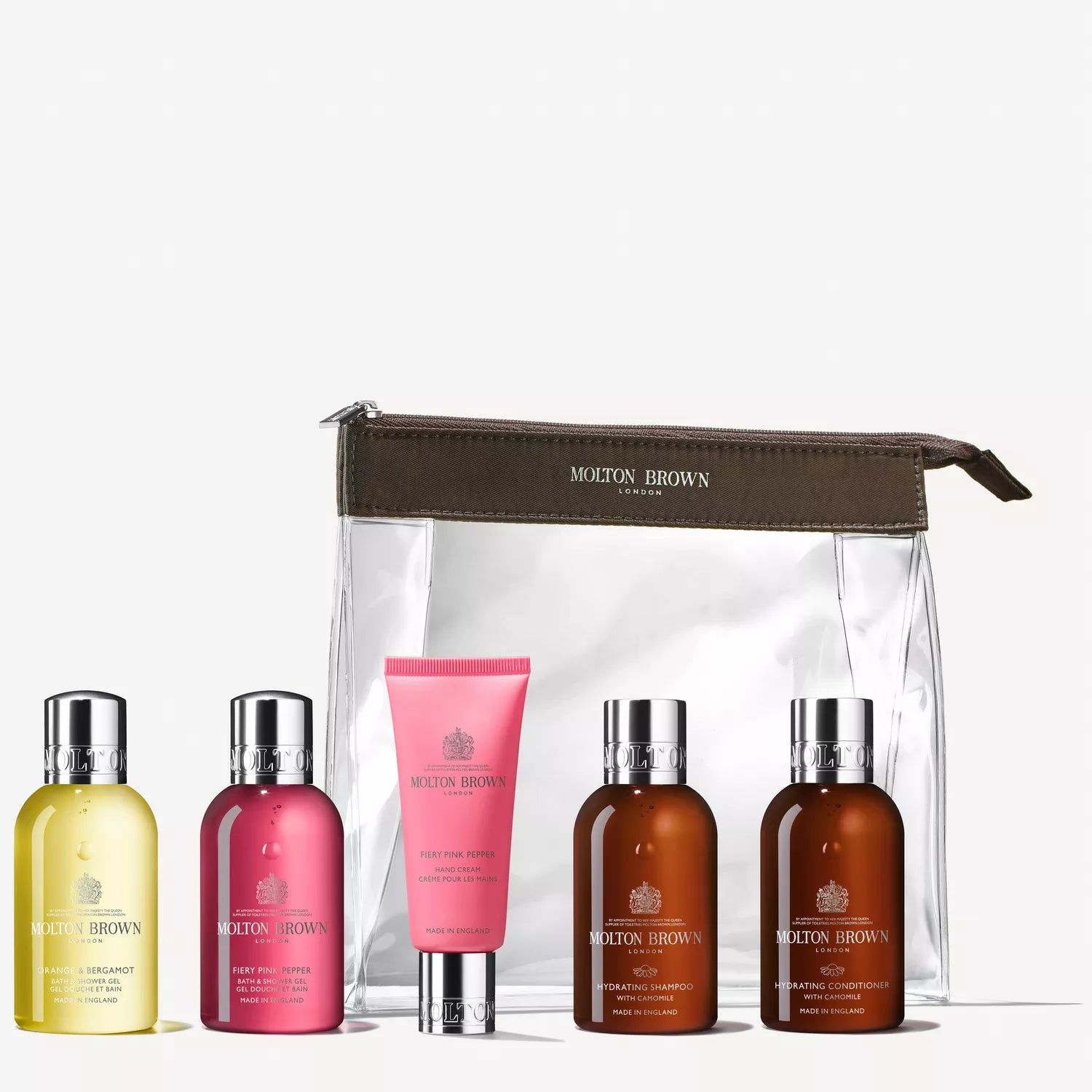 The Revived Voyager Body & Hair Reistas by MoltonBrown Nederlands showcases five luxe travel-sized verzorgingsproducten in yellow, pink, brown, and orange bottles and tubes, neatly arranged in a clear zippered bag.