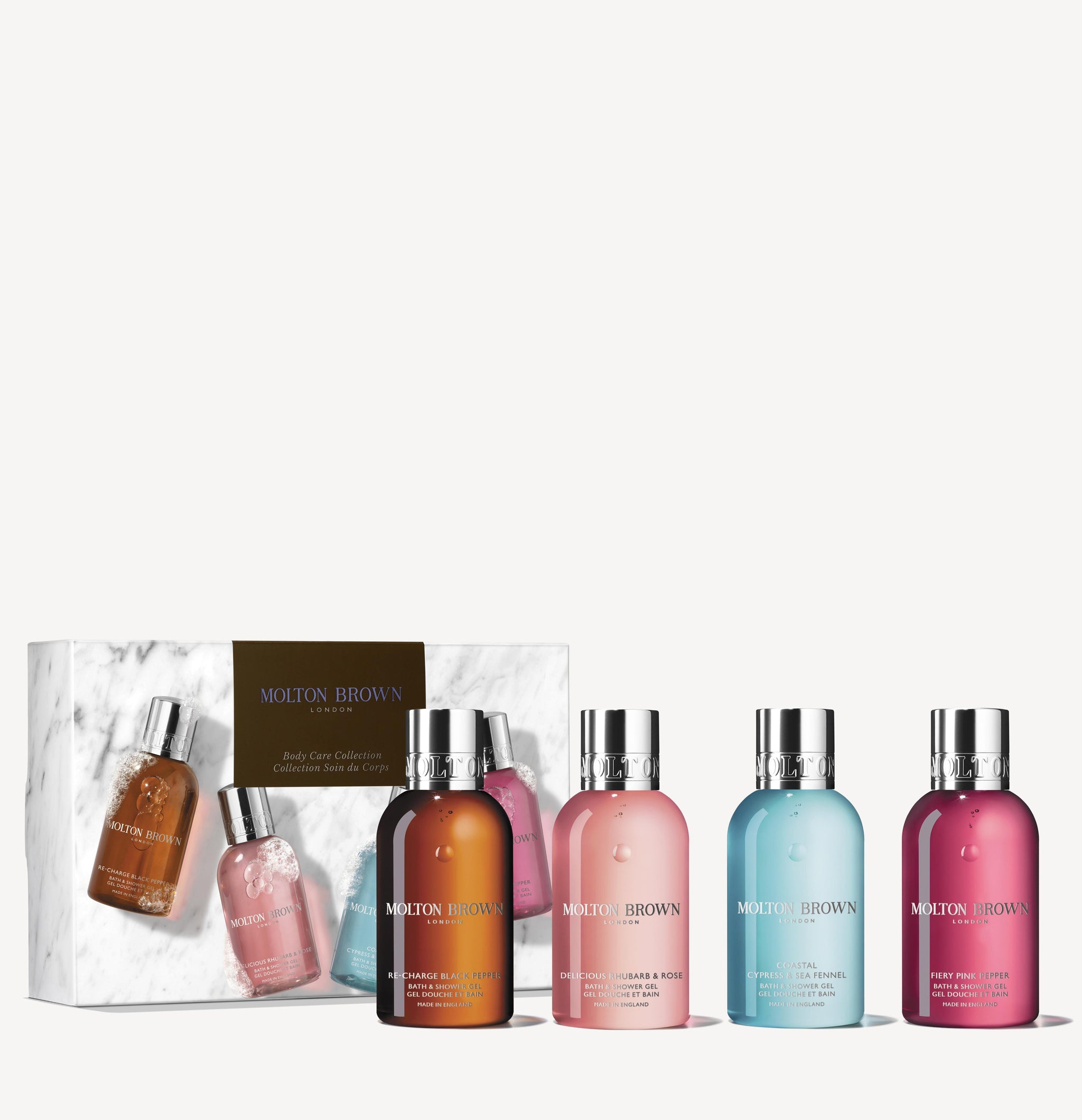 Five MoltonBrown Nederlands douchegels in assorted colors stand before a white marble-effect box featuring their images. Each bottle highlights a unique scent from the Woody & Floral Body Verzorgingscollectie.