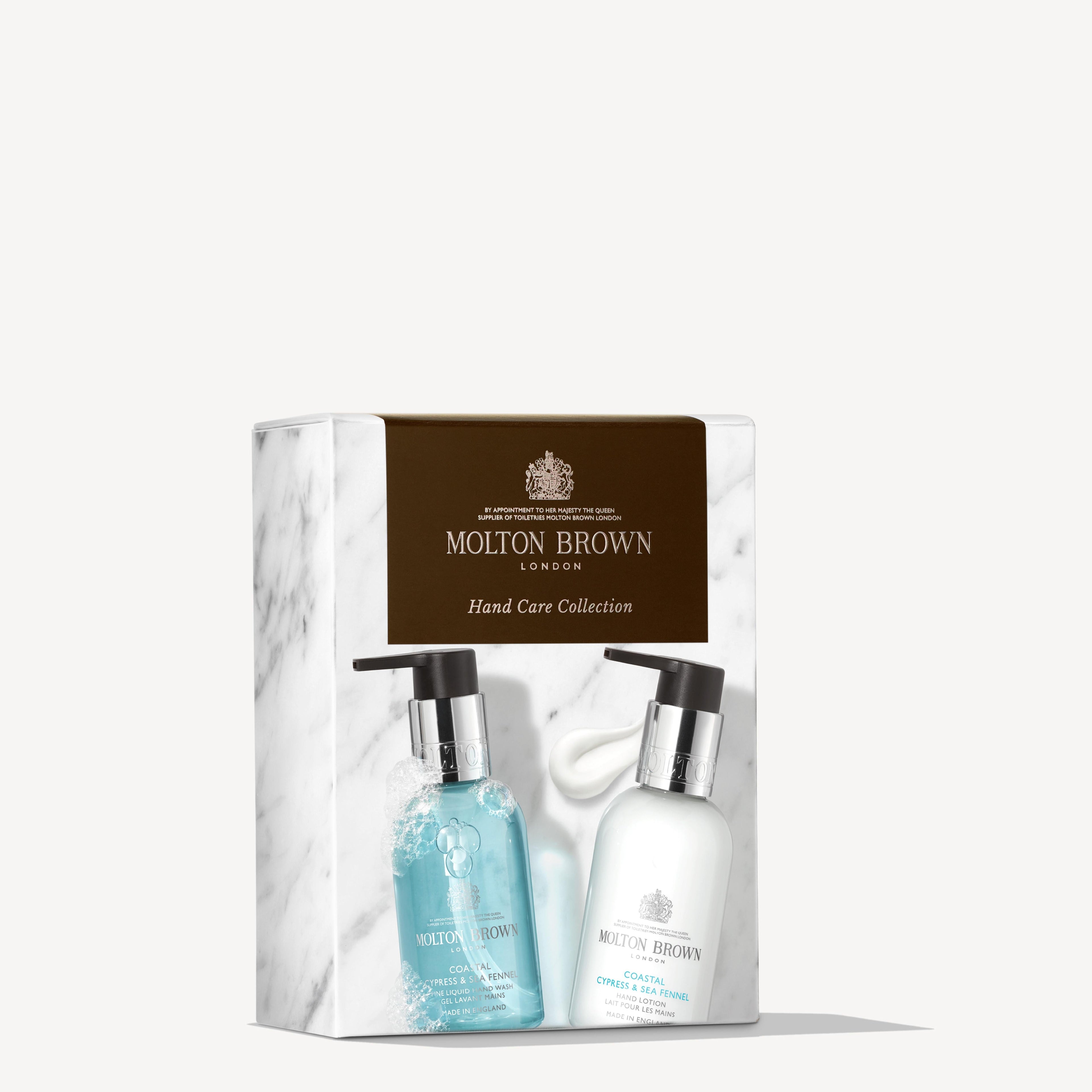 A boxed MoltonBrown Nederlands Coastal Cypress & Sea Fennel Hand Verzorgingscollectie with two pump bottles—one blue and one white—displayed on marble-designed packaging with a brown label, set against a white background.
