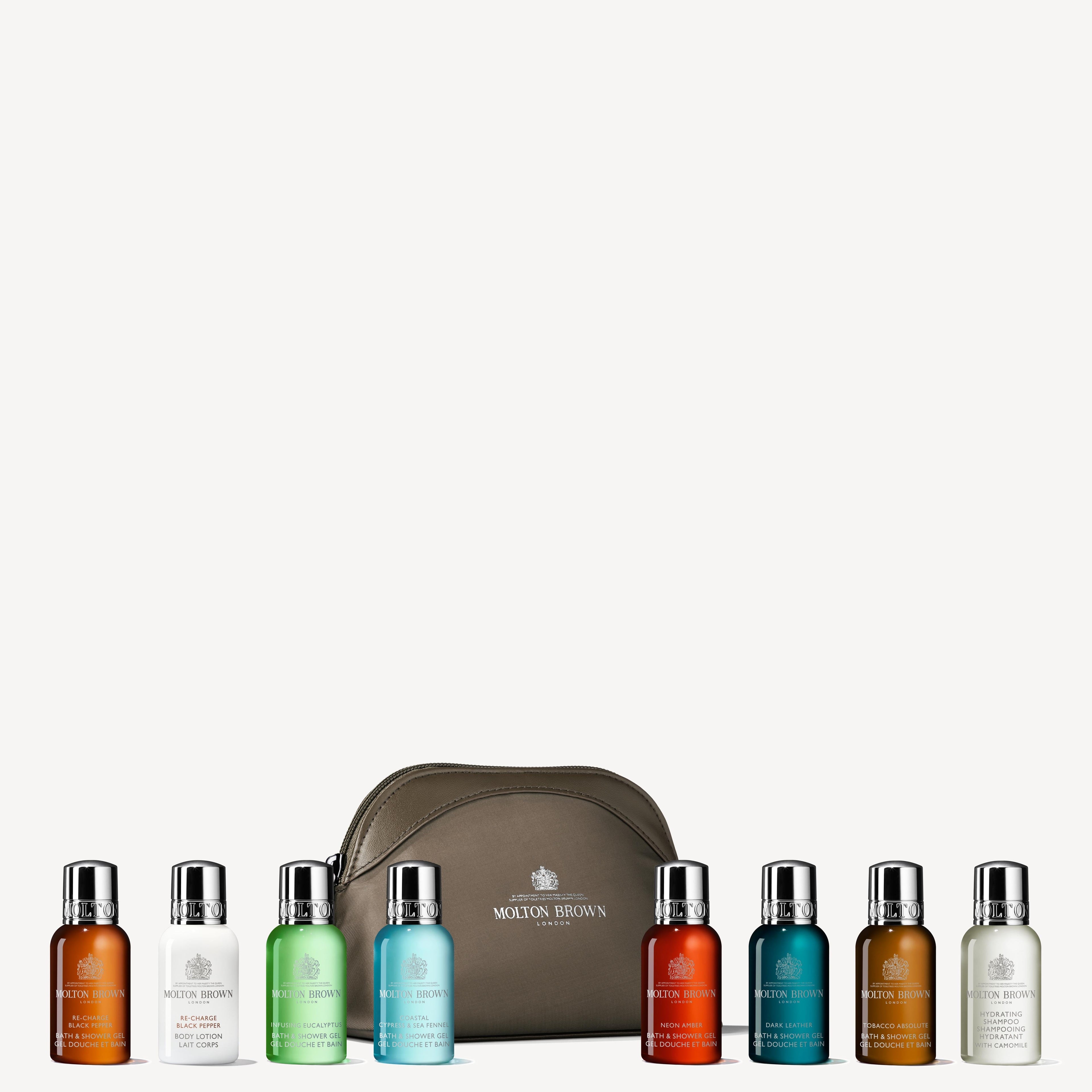 The Classic Explorer Body & Hair Mini Reistas by MoltonBrown Nederlands features eight assorted toiletry minis in vibrant colors, lined up before a taupe zippered bag, all stylishly displayed on a white background.