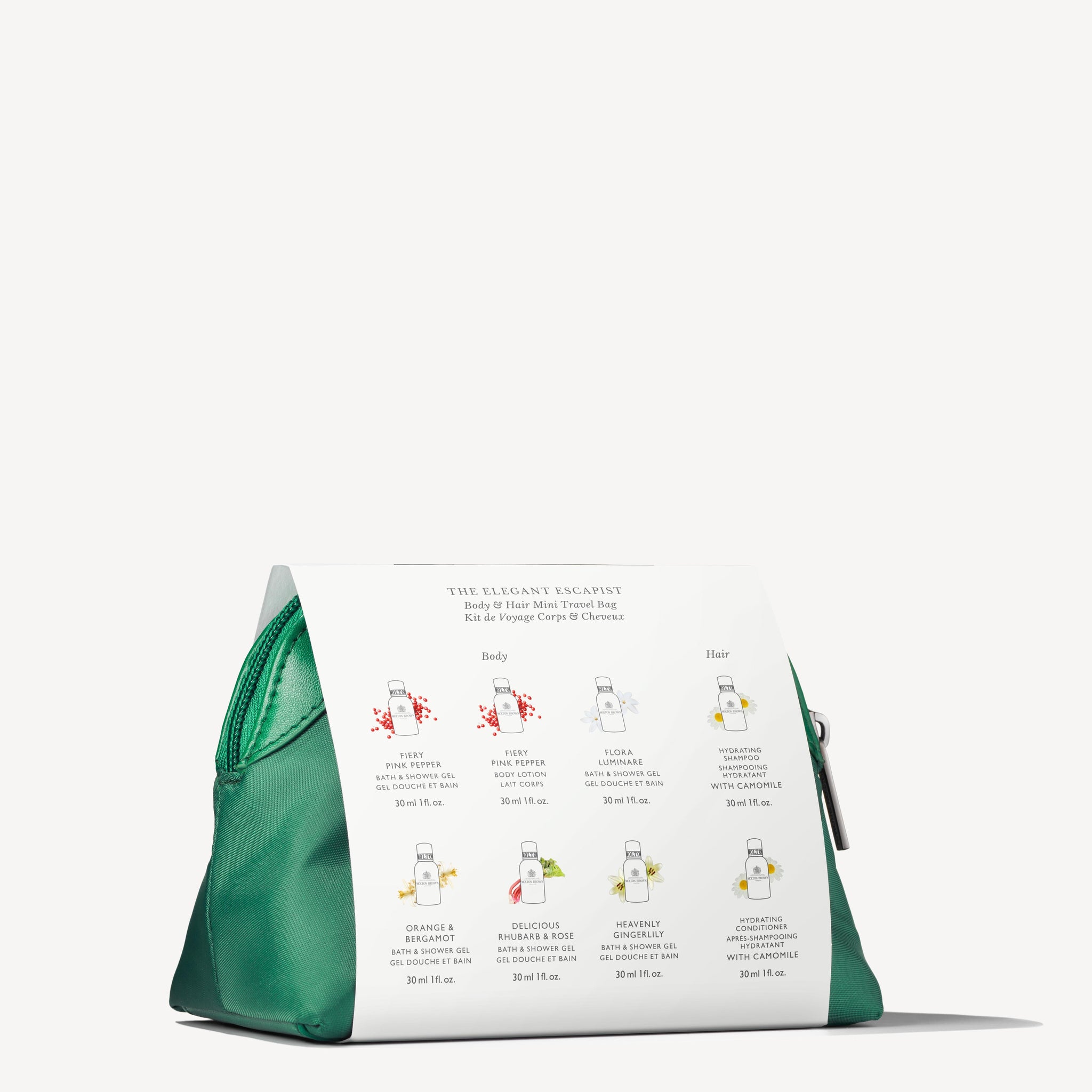 The Elegant Escapist Body & Hair Mini Reistas by MoltonBrown Nederlands is a green zippered bag shown on a white surface with a white card featuring illustrations and details of six travel-size luxury care bottles.