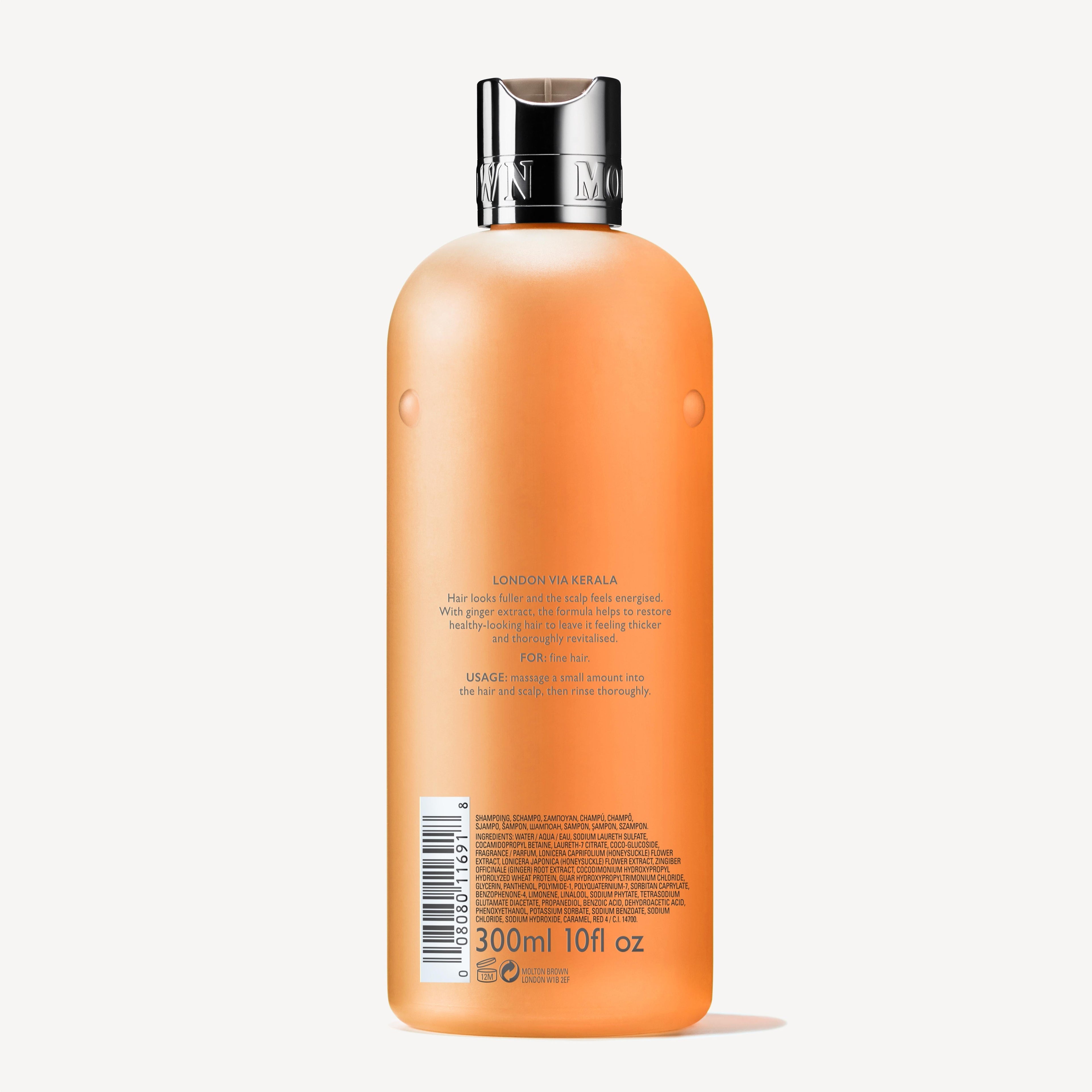 A back view of the MoltonBrown Nederlands Thickening Shampoo With Ginger Extract 300ml shows an orange plastic bottle with a silver cap, product description, barcode, and text. This vegan shampoo is formulated for volume and fijn haar.