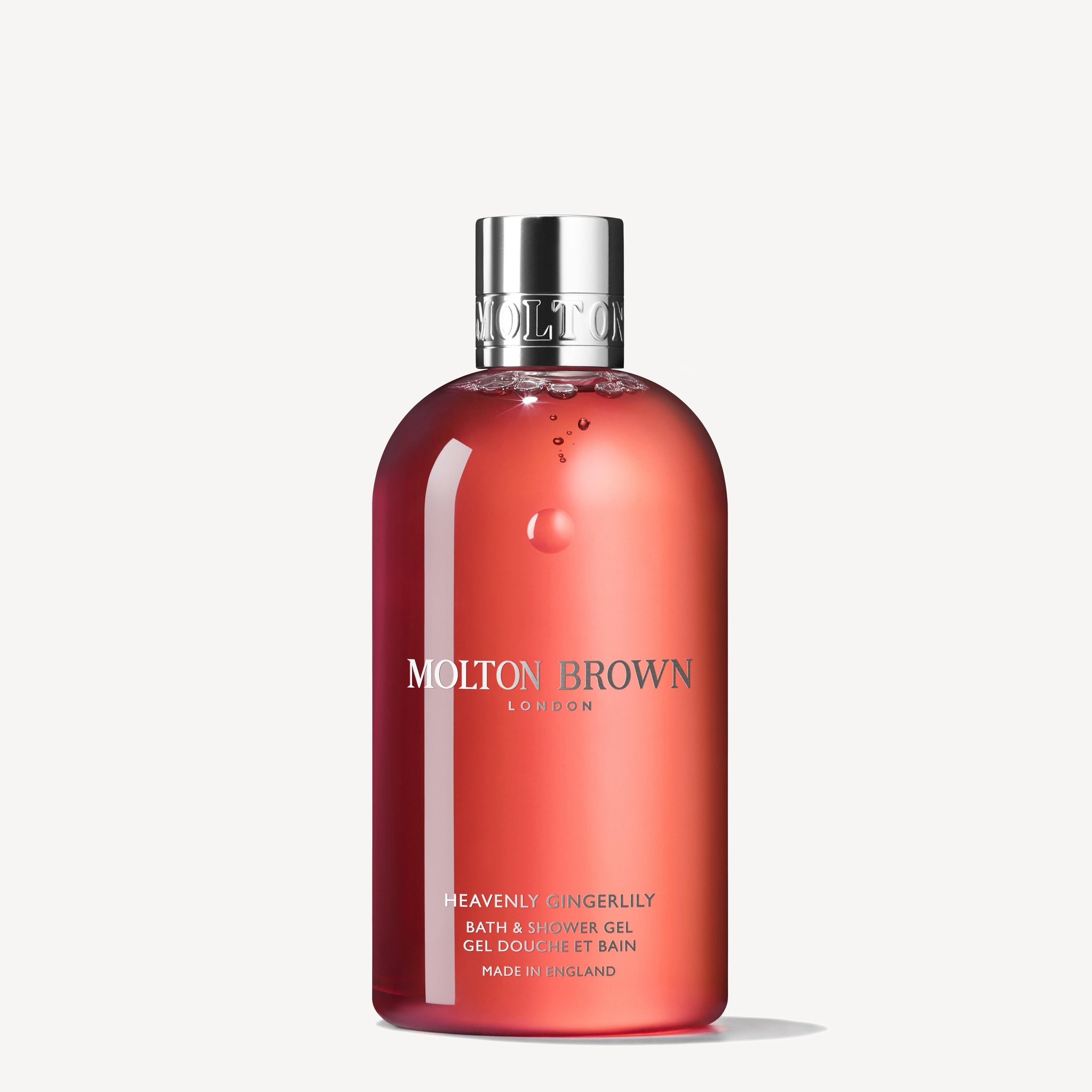 A 300ml bottle of MoltonBrown Nederlands Heavenly Gingerlily Bad- & Douchegel met zilveren dop en roze, bloemige douchegel met gember staat rechtop op een witte achtergrond.