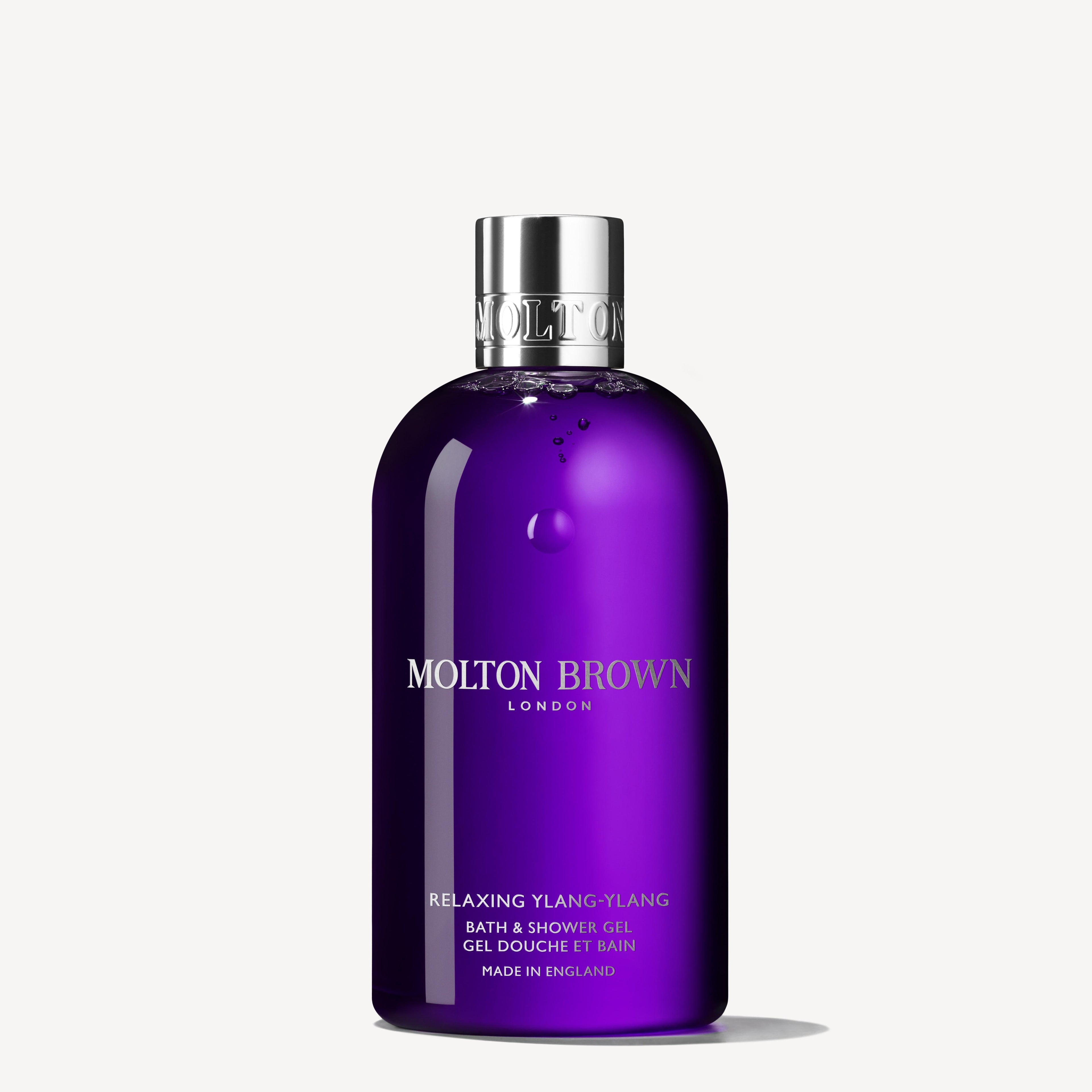 A paarse fles MoltonBrown Nederlands Relaxing Ylang-Ylang Bad- & Douchegel 300ml met glanzende zilveren dop, rechtop tegen een witte achtergrond—ideaal voor pure ontspanning.