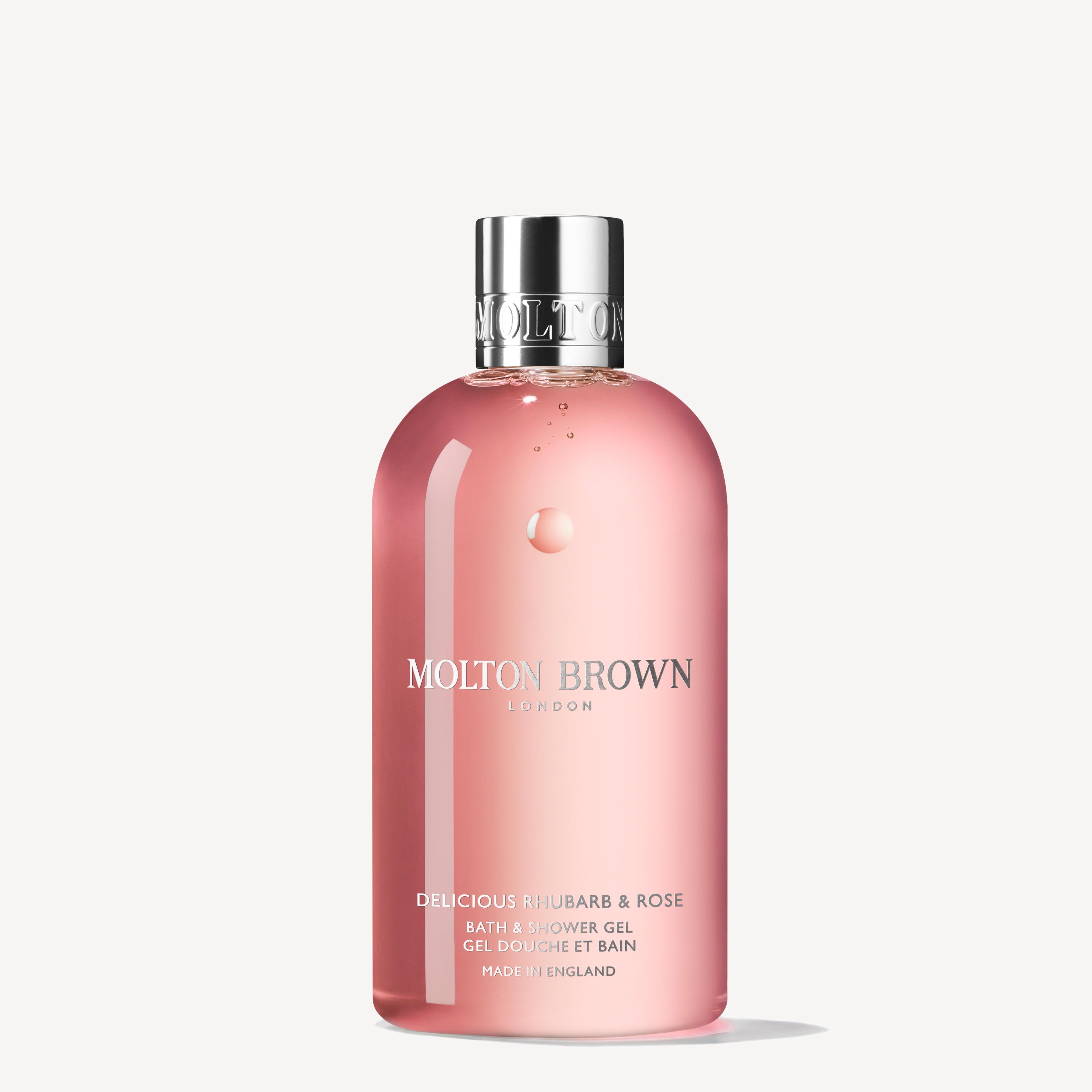 A clear pink 300ml bottle of MoltonBrown Nederlands Delicious Rhubarb & Rose Bad- & Douchegel, with a silver cap, stands upright against a plain white background.