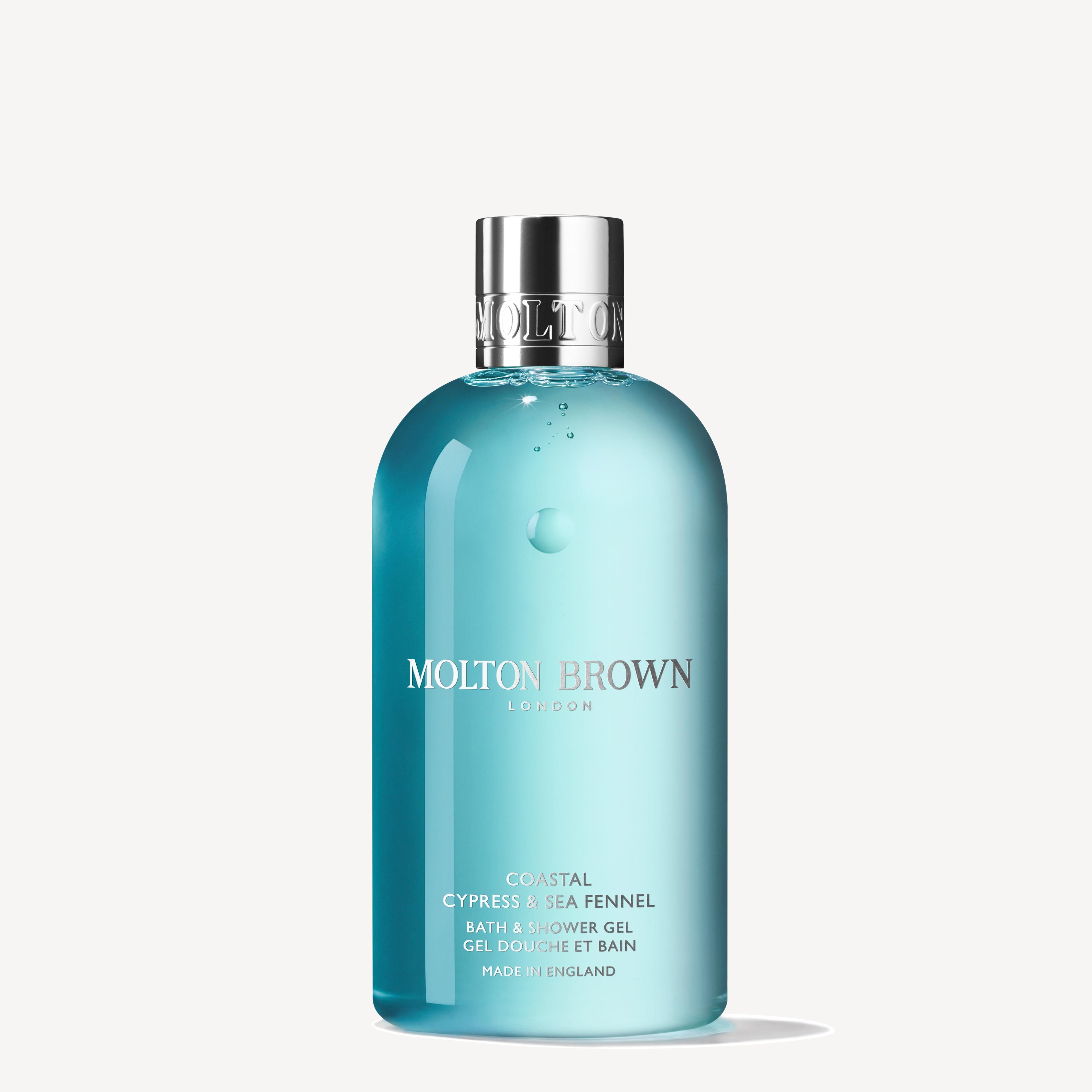 A blue 300ml bottle of MoltonBrown Nederlands Coastal Cypress & Sea Fennel Bad- & Douchegel with a silver cap stands upright against a plain white background.