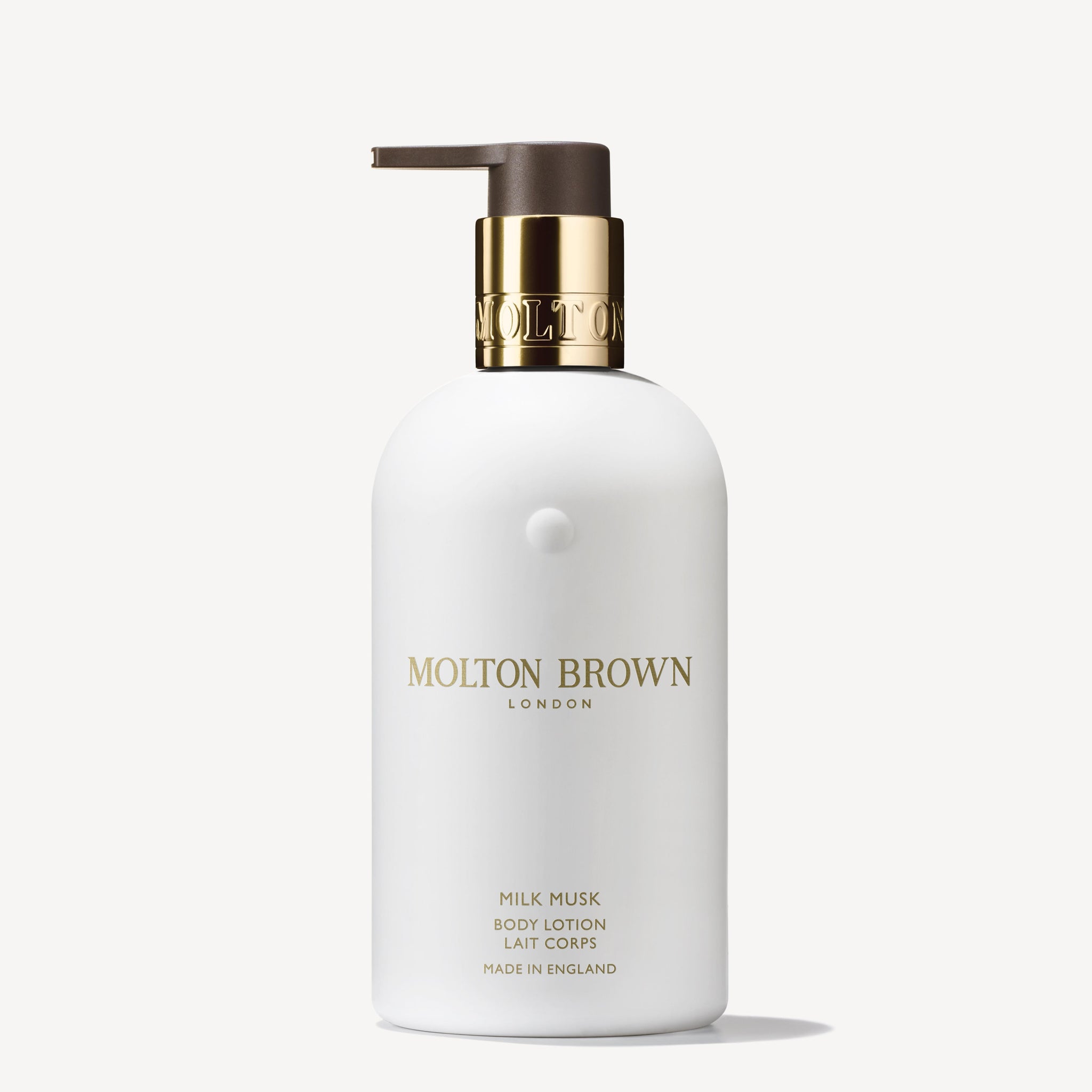 A 300ml white bottle of MoltonBrown Nederlands Milk Musk Bodylotion, with a gold and brown pump and gold lettering, set on a plain white background. Perfect for skin hydration.