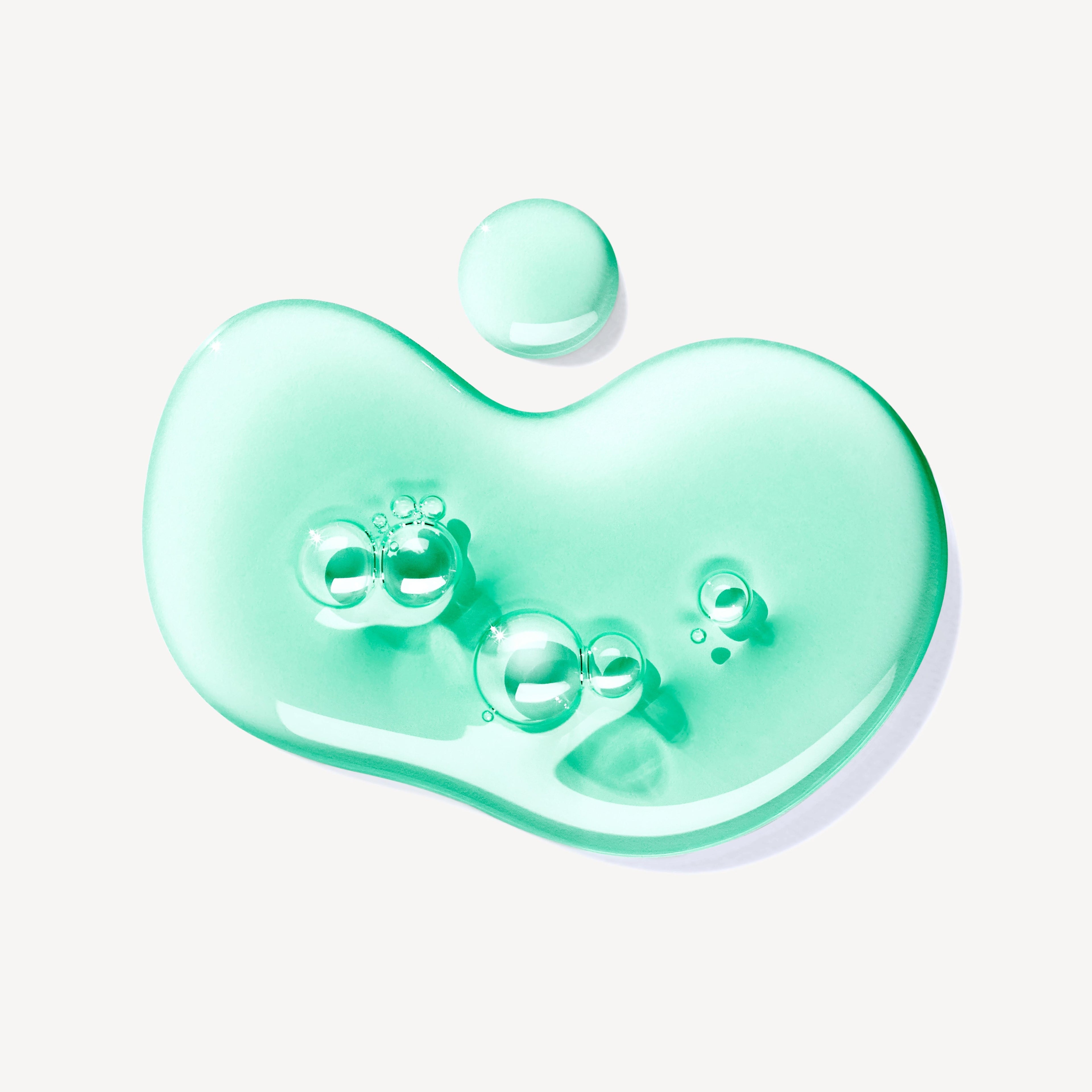 A puddle of translucent mint green MoltonBrown Nederlands Wild Mint & Lavandin Bad- & Douchegel 300ml, featuring air bubbles and infused with wild mint and lavandin, is shown against a white background.