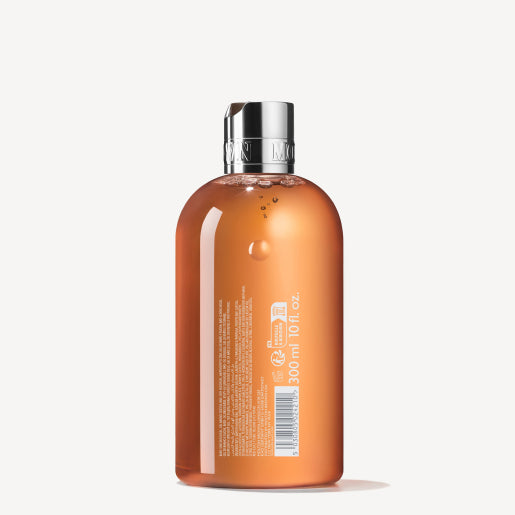 A clear orange plastic bottle with a silver cap contains MoltonBrown Nederlands Sunlit Clementine & Vetiver Bad- & Douchegel 300ml. White text and graphics, plus product and barcode details, appear on the plain white background.