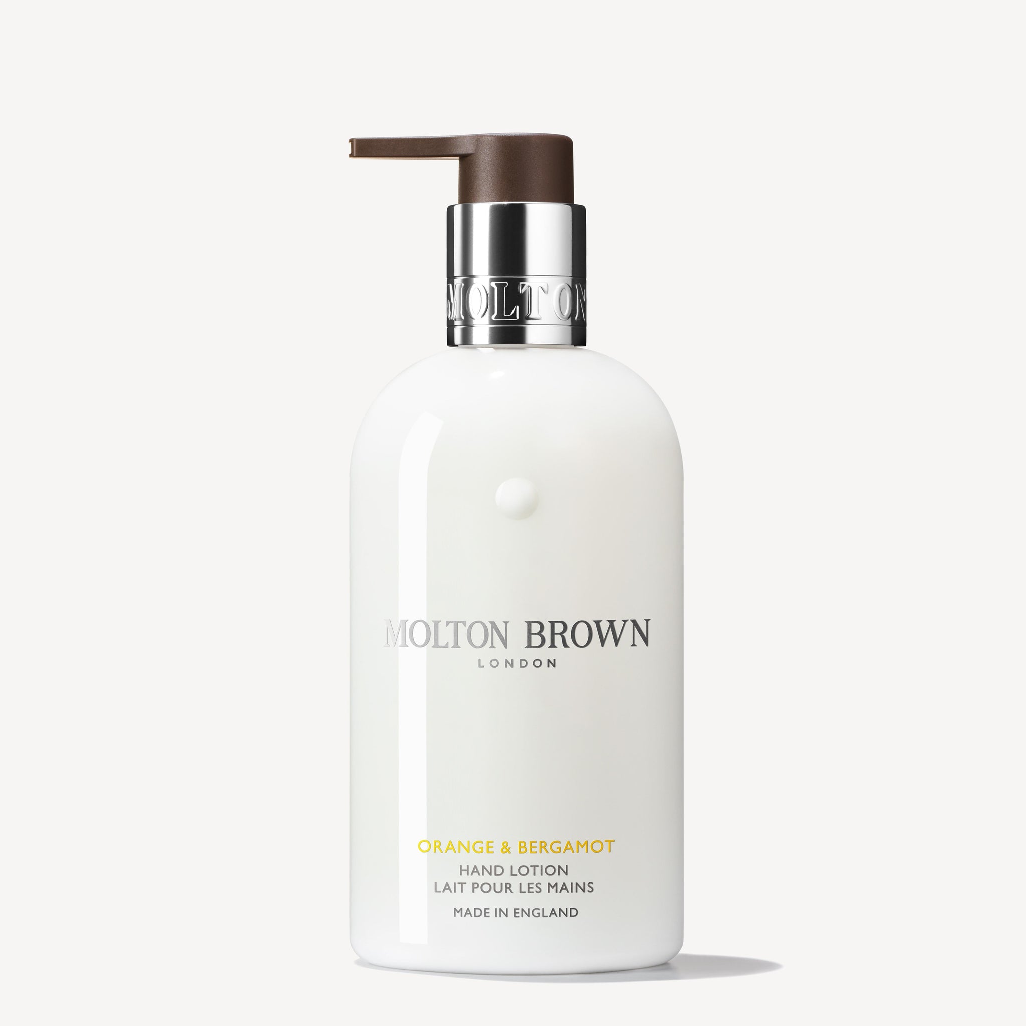 A 300ml bottle of MoltonBrown Nederlands Orange & Bergamot Handlotion with a brown pump and silver collar stands upright against a plain white background.