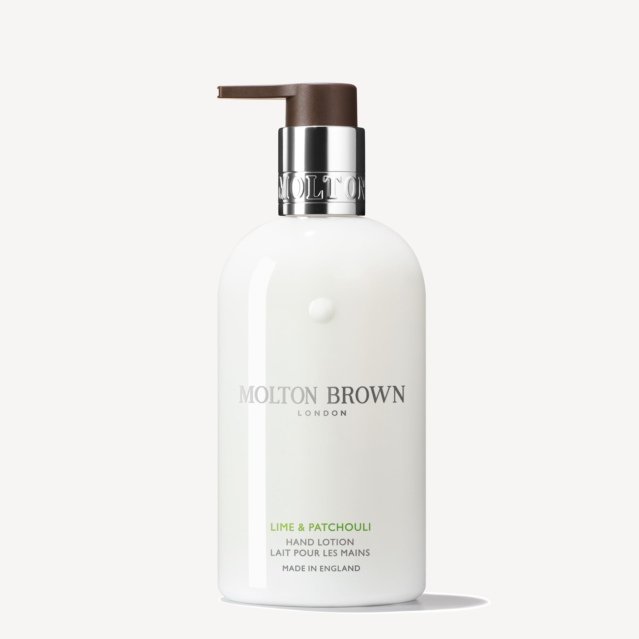 A white 300ml bottle of MoltonBrown Nederlands Lime & Patchouli Handlotion with a brown pump and silver collar stands upright against a plain white background.