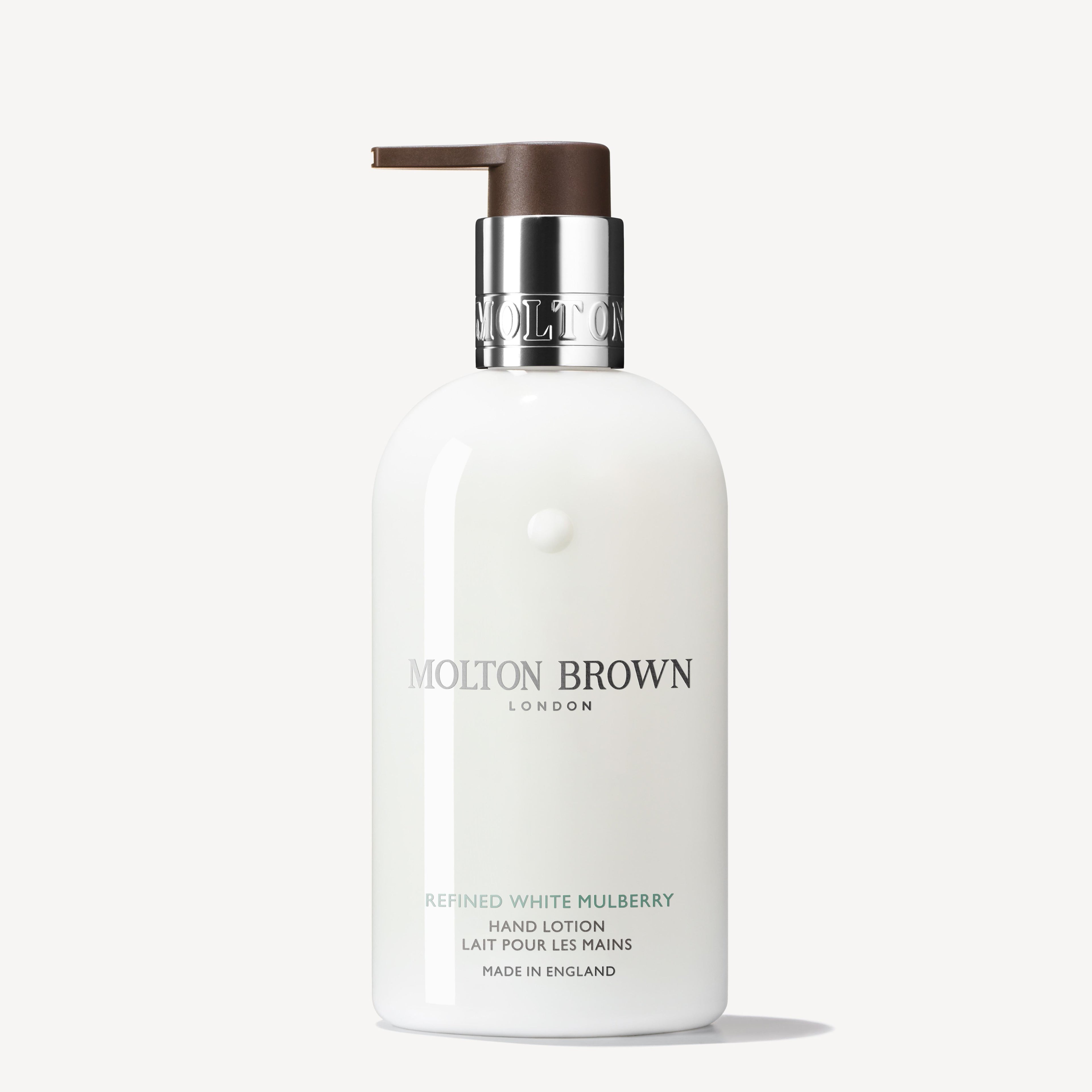 A white bottle of MoltonBrown Nederlands Refined White Mulberry Fijne Vloeibare Handlotion 300ml with a brown pump, silver-grey text, and green accents, enriched with jasmijn and witte moerbei extract, set against a plain white background.