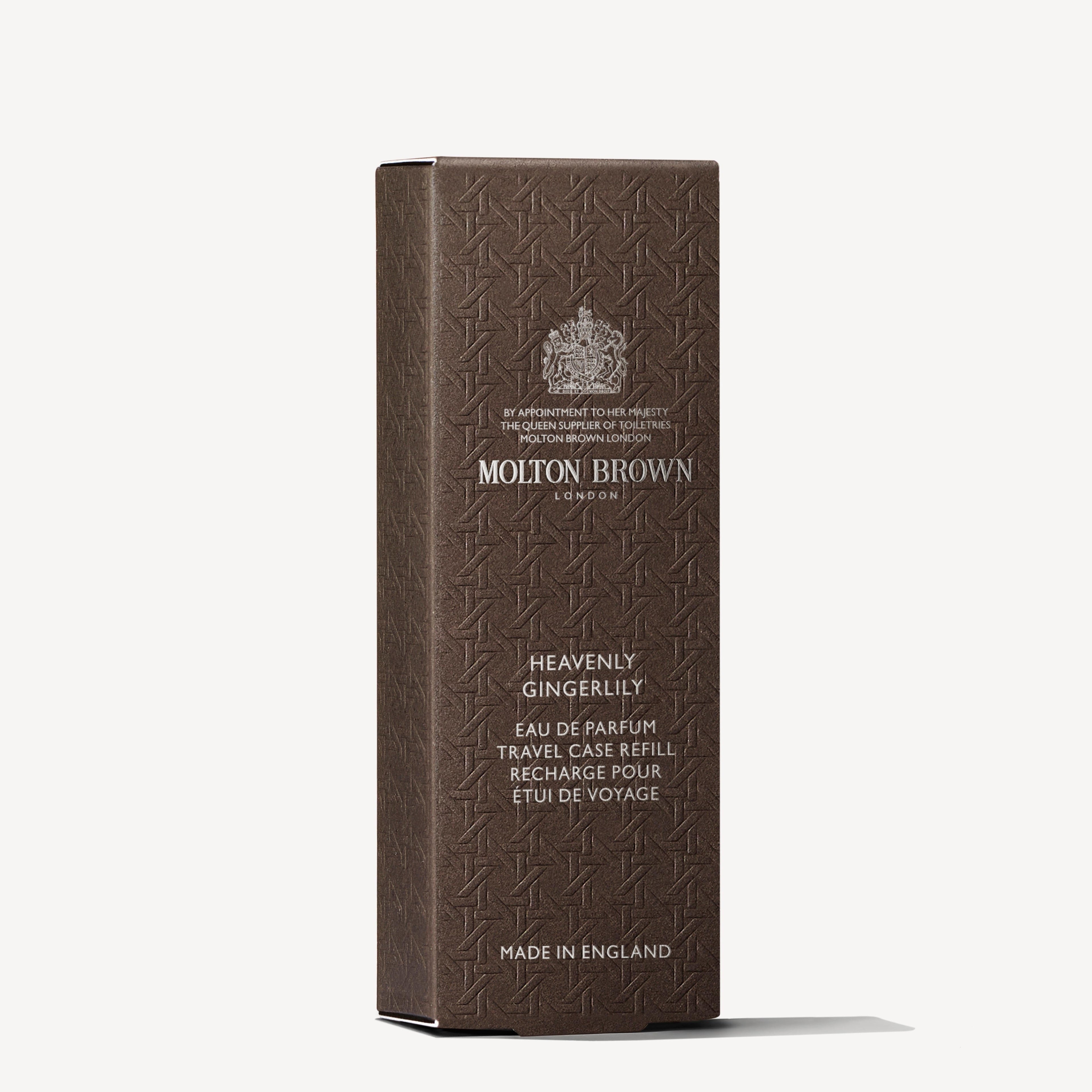 A brown rectangular box of MoltonBrown Nederlands Heavenly Gingerlily Eau de Parfum Reiskoffer Navulling 7.5ml with embossed patterns and silver text stands upright against a white background, inspired by delicate jasmijn scent.